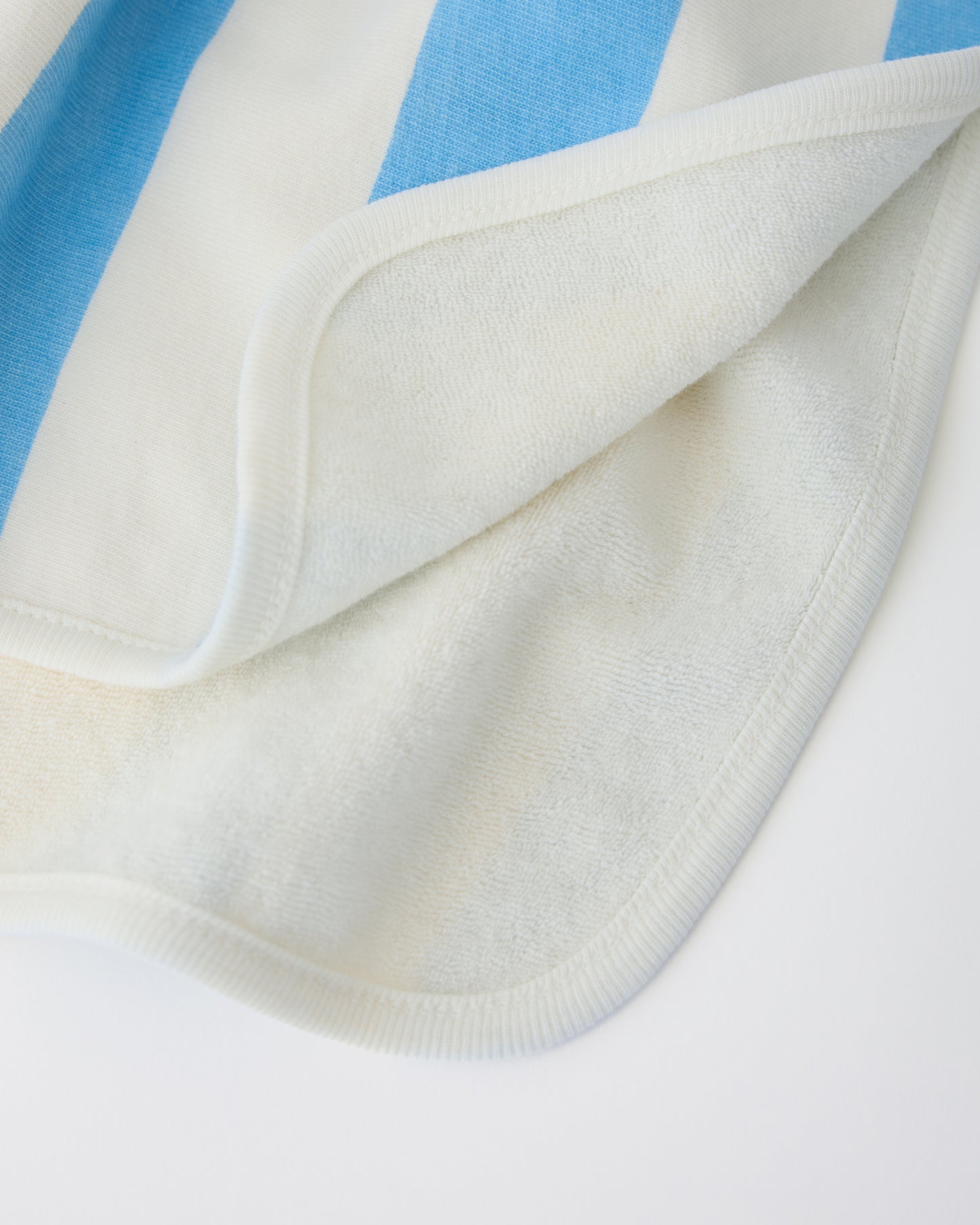 Close up of inside soft towel texture on Toddler Poncho Towel in Blue Wide Stripe on a beige background