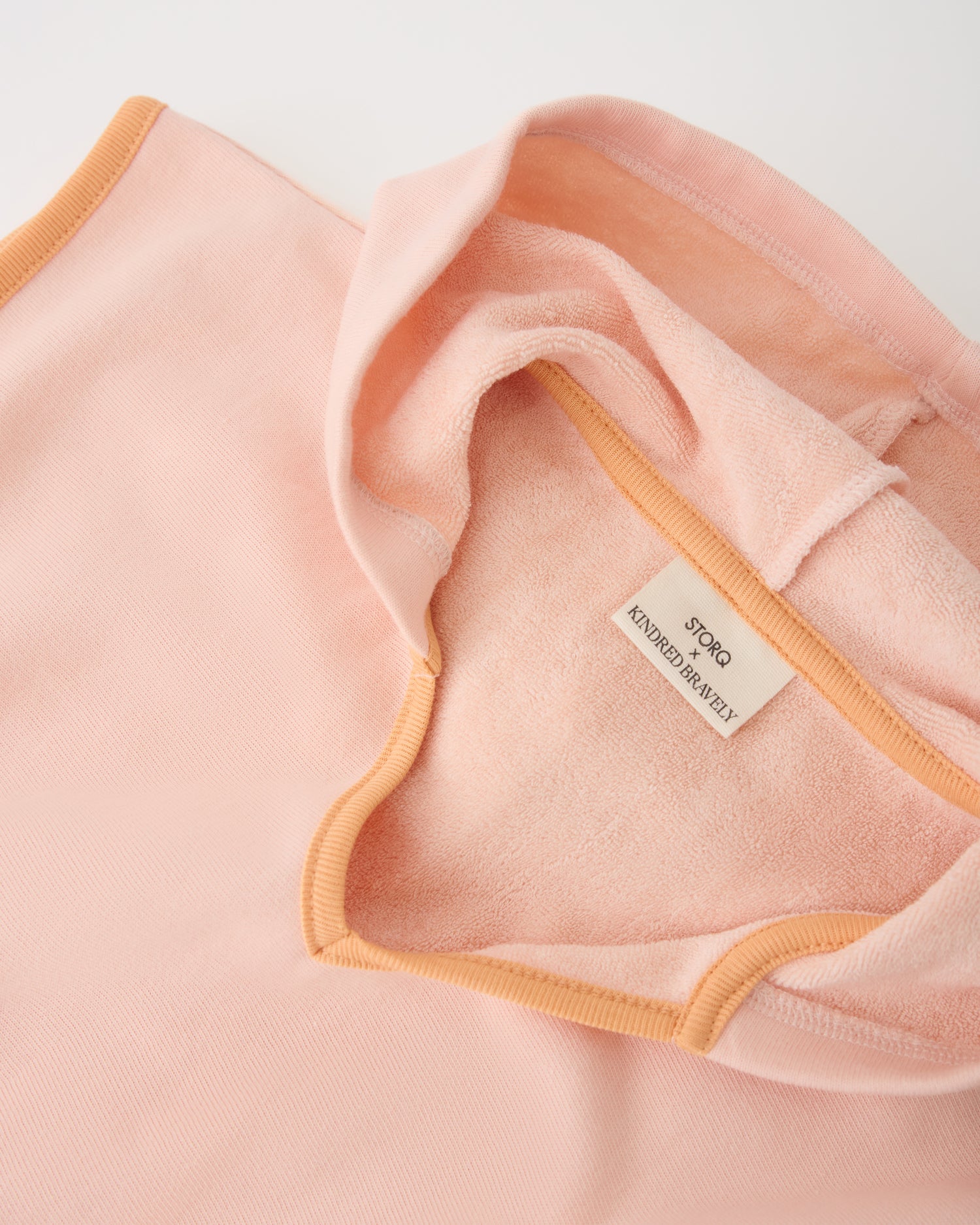 Close up of hood on Toddler Poncho Towel in Peach Whip on a beige background