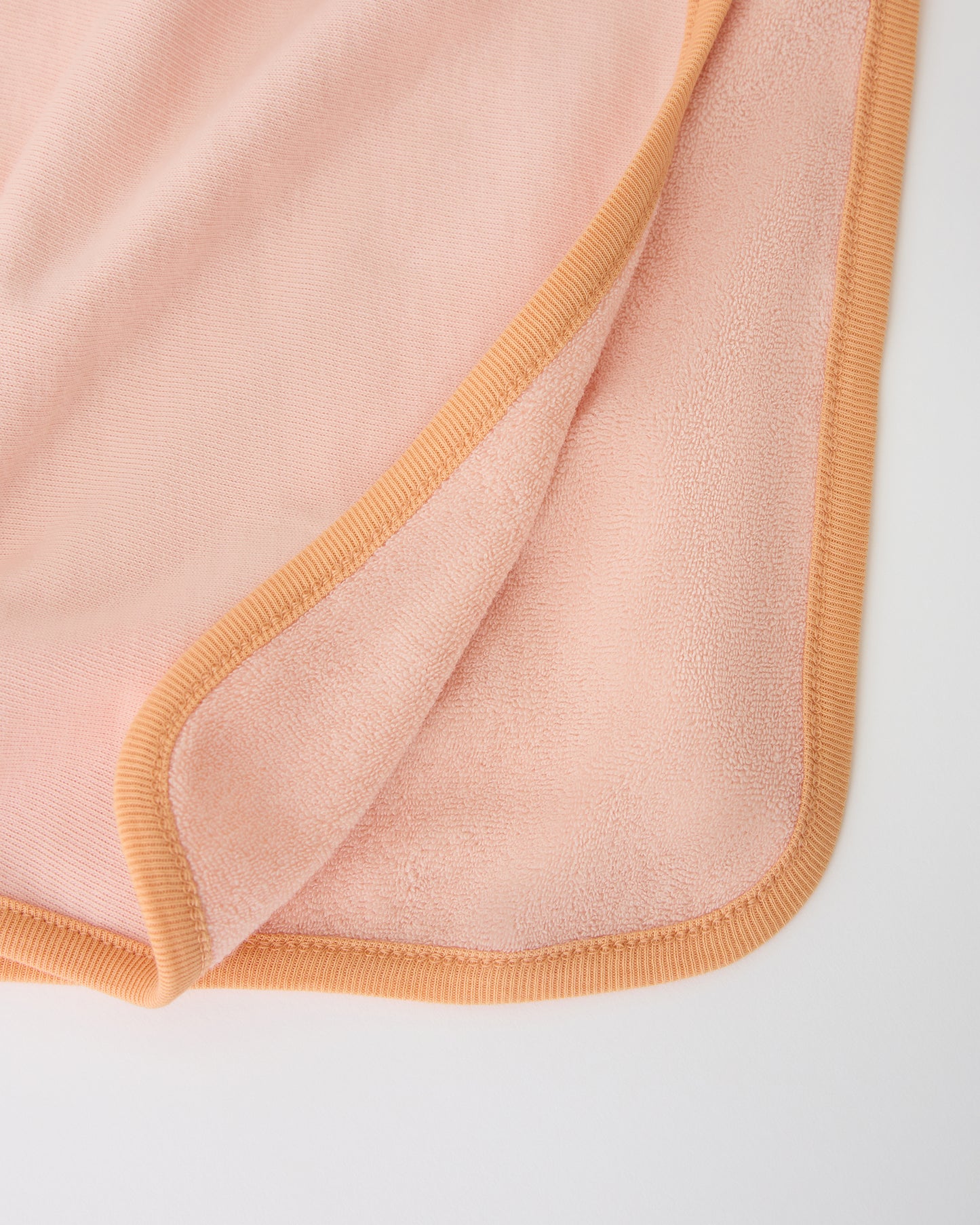 Close up of inside soft towel texture on Toddler Poncho Towel in Peach Whip on a beige background
