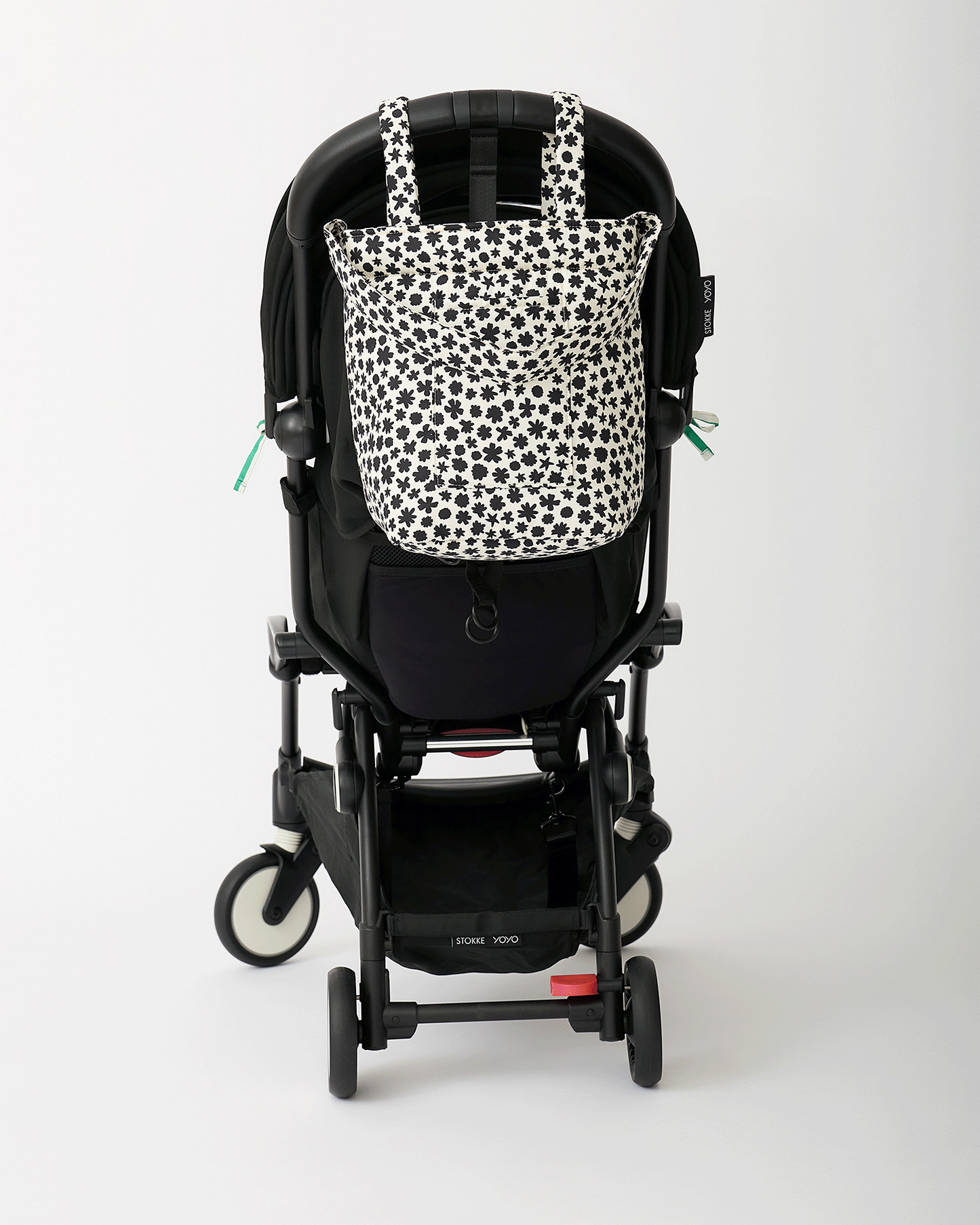Animated Gif of black stroller rotating with Stroller Party™ Seat Liner & Strap Covers in Green Stripe, and Stroller Party™ Bucket Bag in Cream Chamomiles hanging off the handlebars, on an off white background.