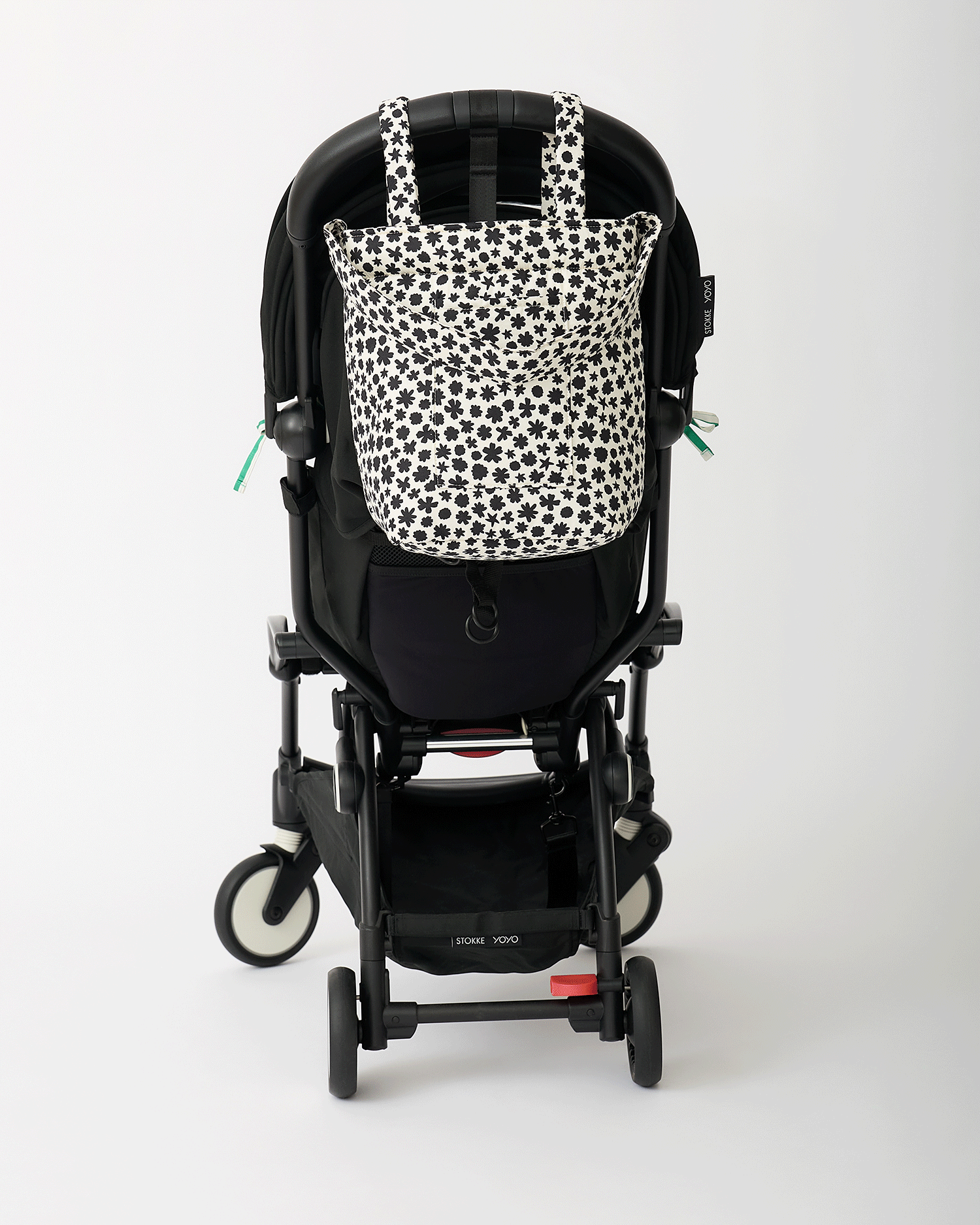 Animated Gif of black stroller rotating with Stroller Party™ Seat Liner & Strap Covers in Green Stripe, and Stroller Party™ Bucket Bag in Cream Chamomiles hanging off the handlebars, on an off white background.