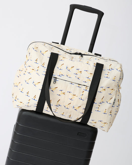 Large Weekender Bag in Ivory Ski is set ontop of a suitcase, on an off white background.
