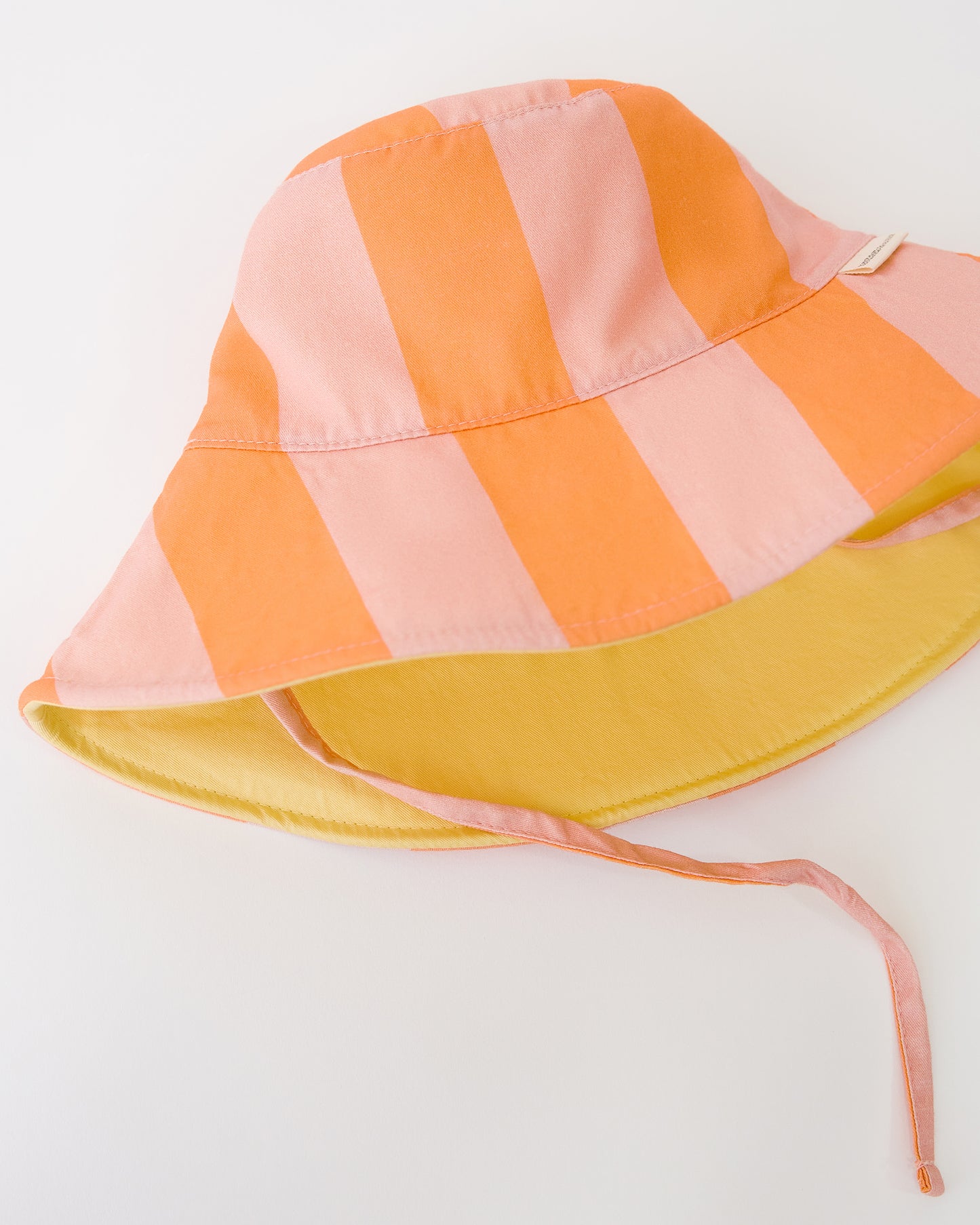 Close up view of Toddler Sun Hat in Pink Wide Stripe on a beige background