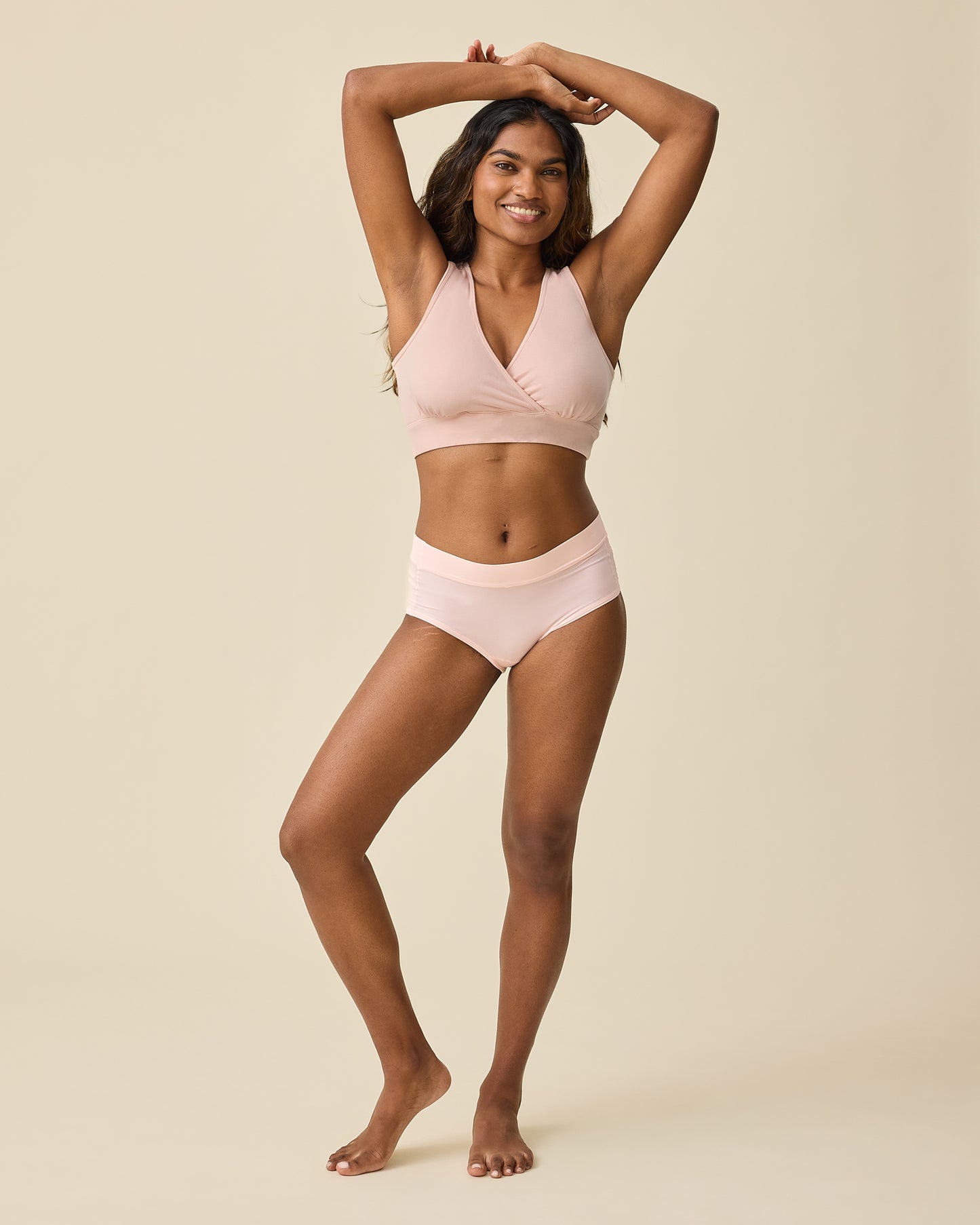 Model is wearing Grow with Me™ Maternity & Postpartum Brief in Soft Pink on a beige background