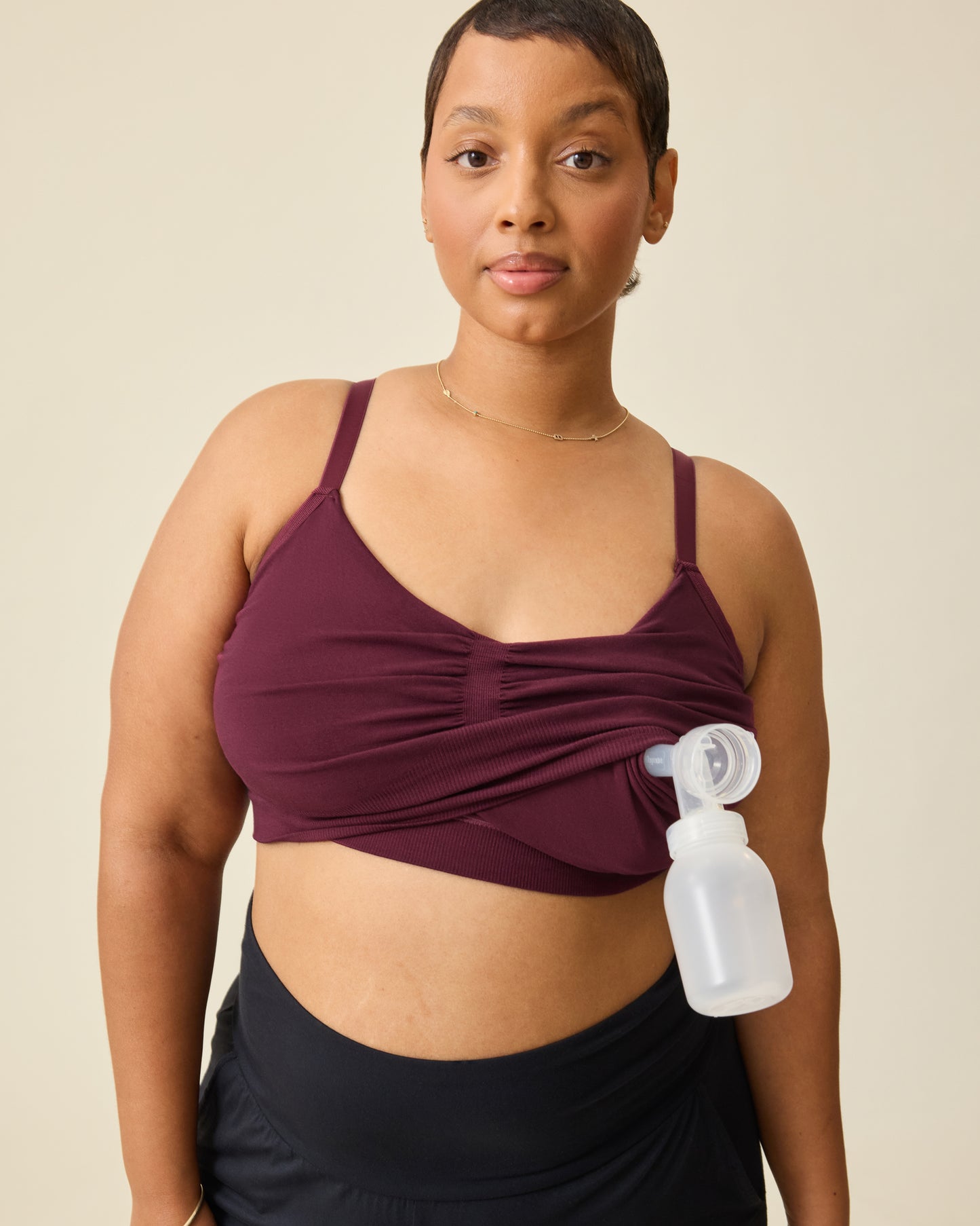 Woman wearing the Sublime® Bamboo Hands-Free Pumping Lounge & Sleep Bra in Deep Burgundy with pump flange and bottle inserted.