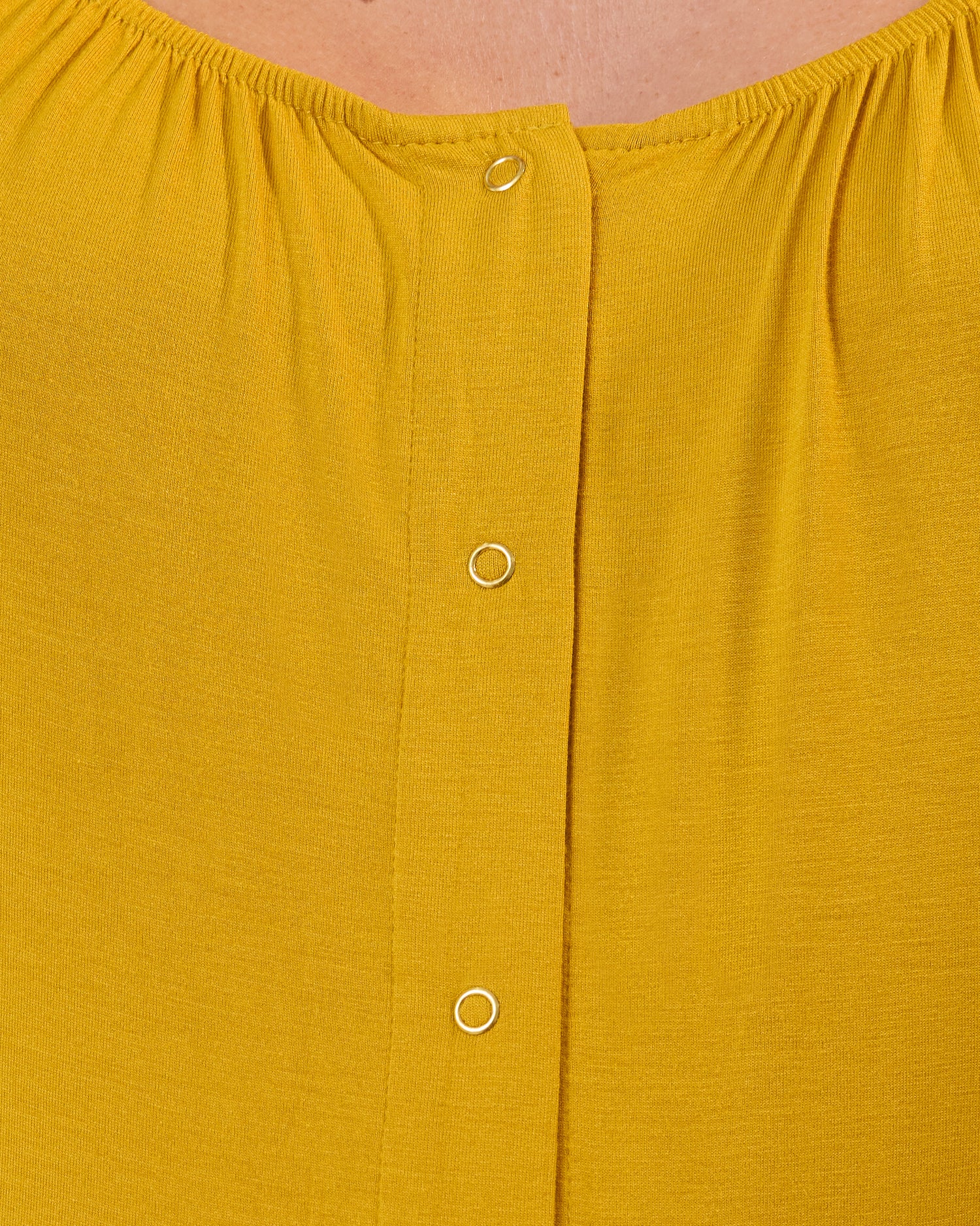 Close-up of a mustard fabric from Woman wearing the Ruffle Strap Labor & Delivery Gown in Honey with snap details.