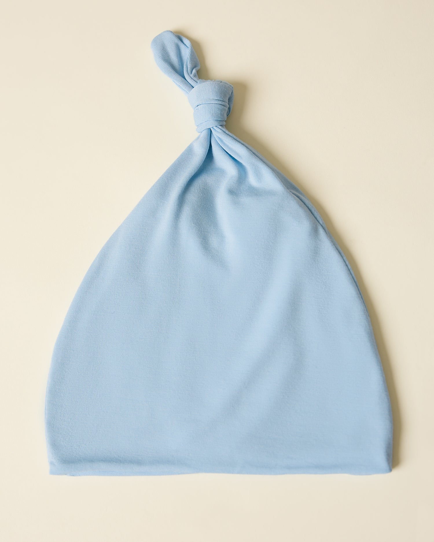 Light French blue baby hat on a beige background