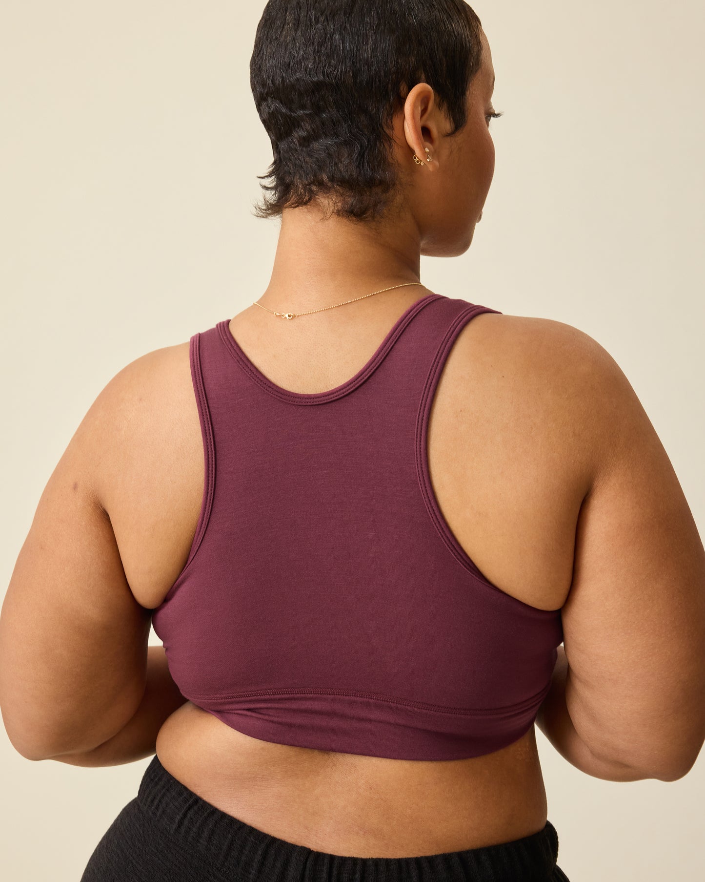 Back view of Model wearing French Terry Racerback Nursing & Sleep Bra in Deep Burgundy on a beige background