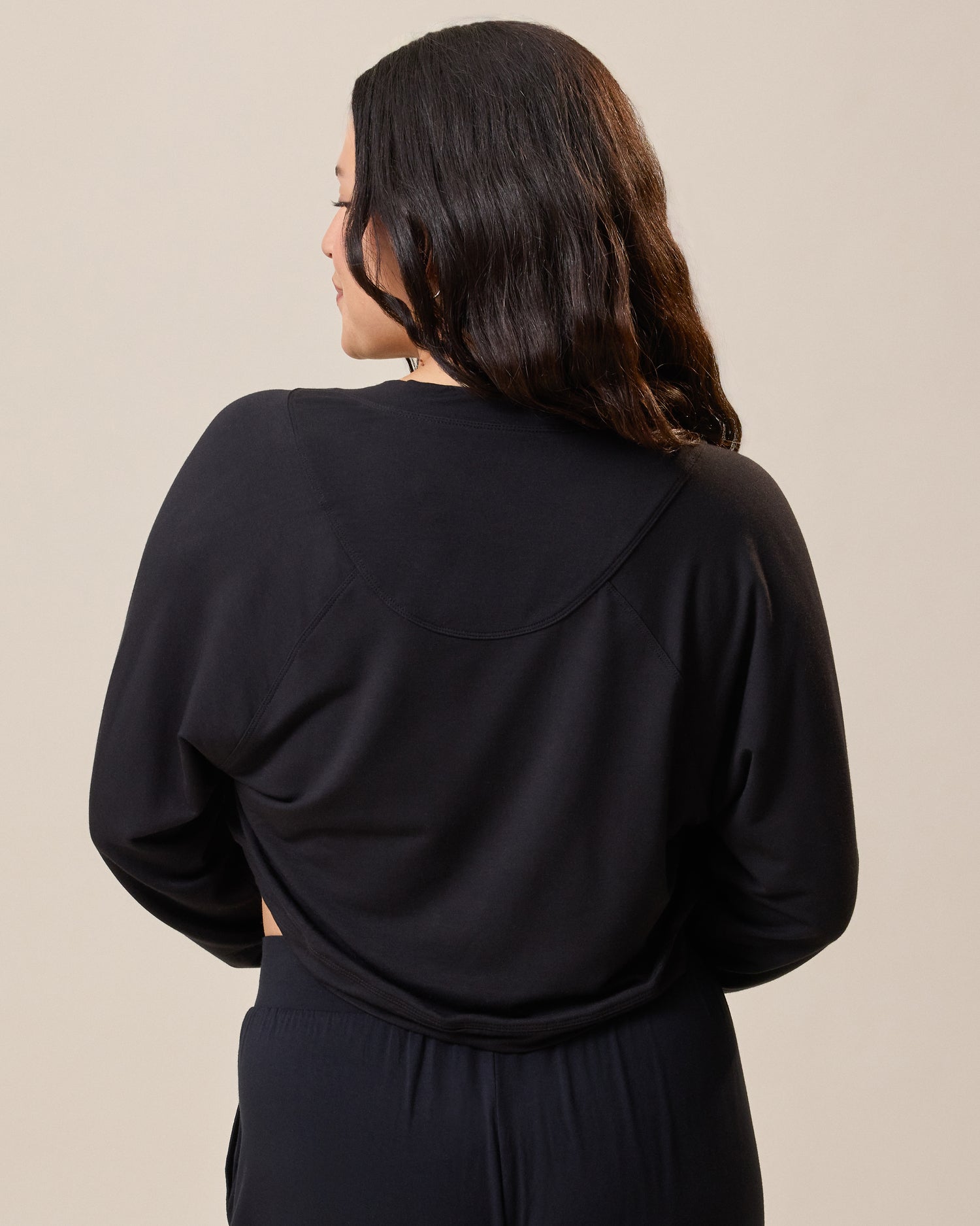 Back of the French Terry Cardigan Shrug in black on model against a beige background
