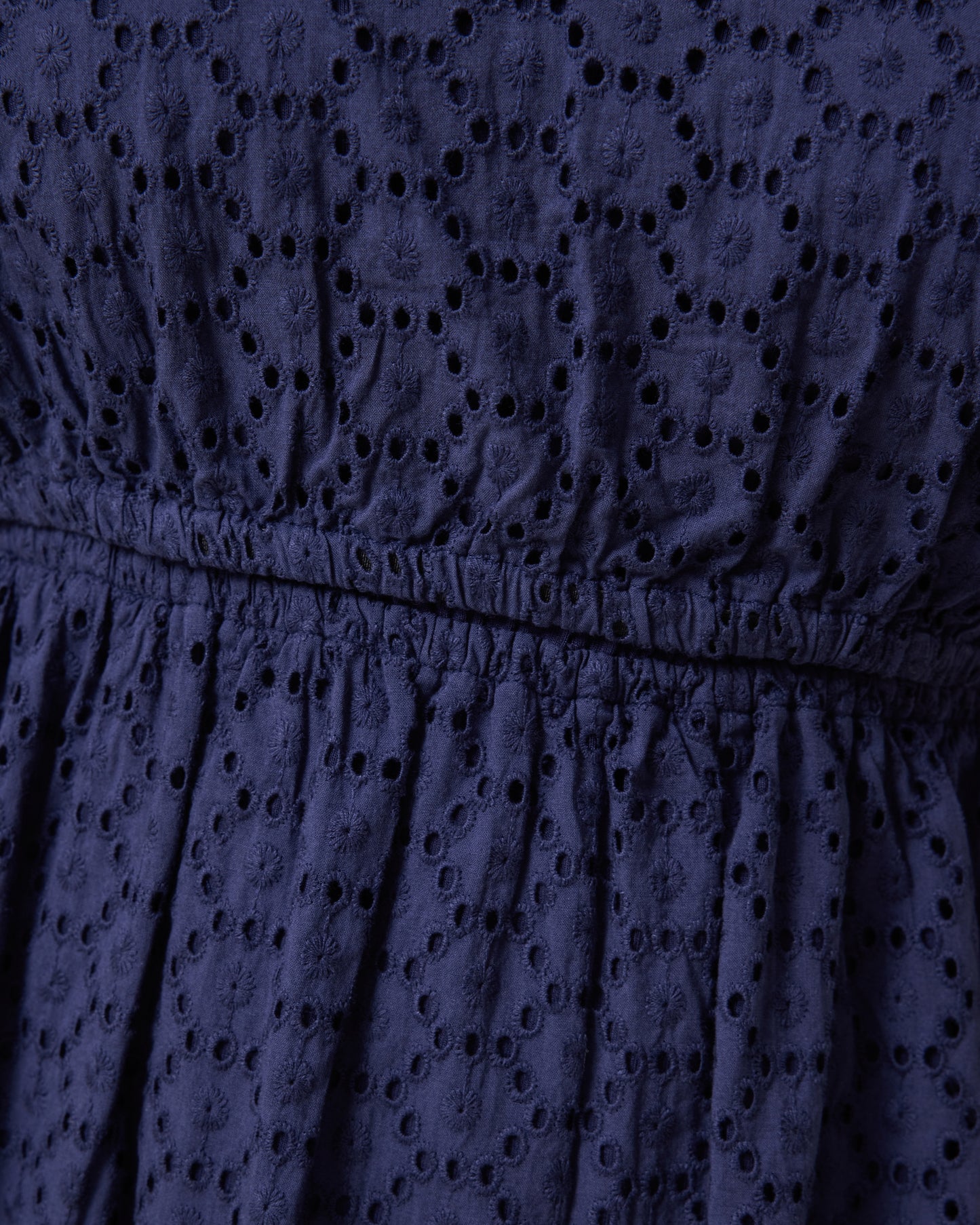 Close-up of a navy blue dress with eyelet detailing