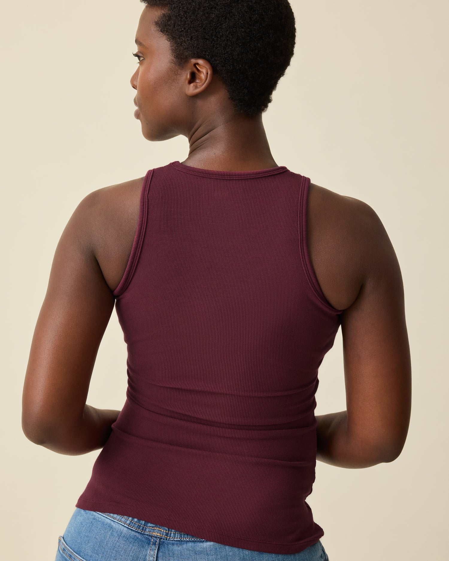 Woman wearing deep burgundy Ribbed Bamboo Racerback Nursing Tank against a beige background