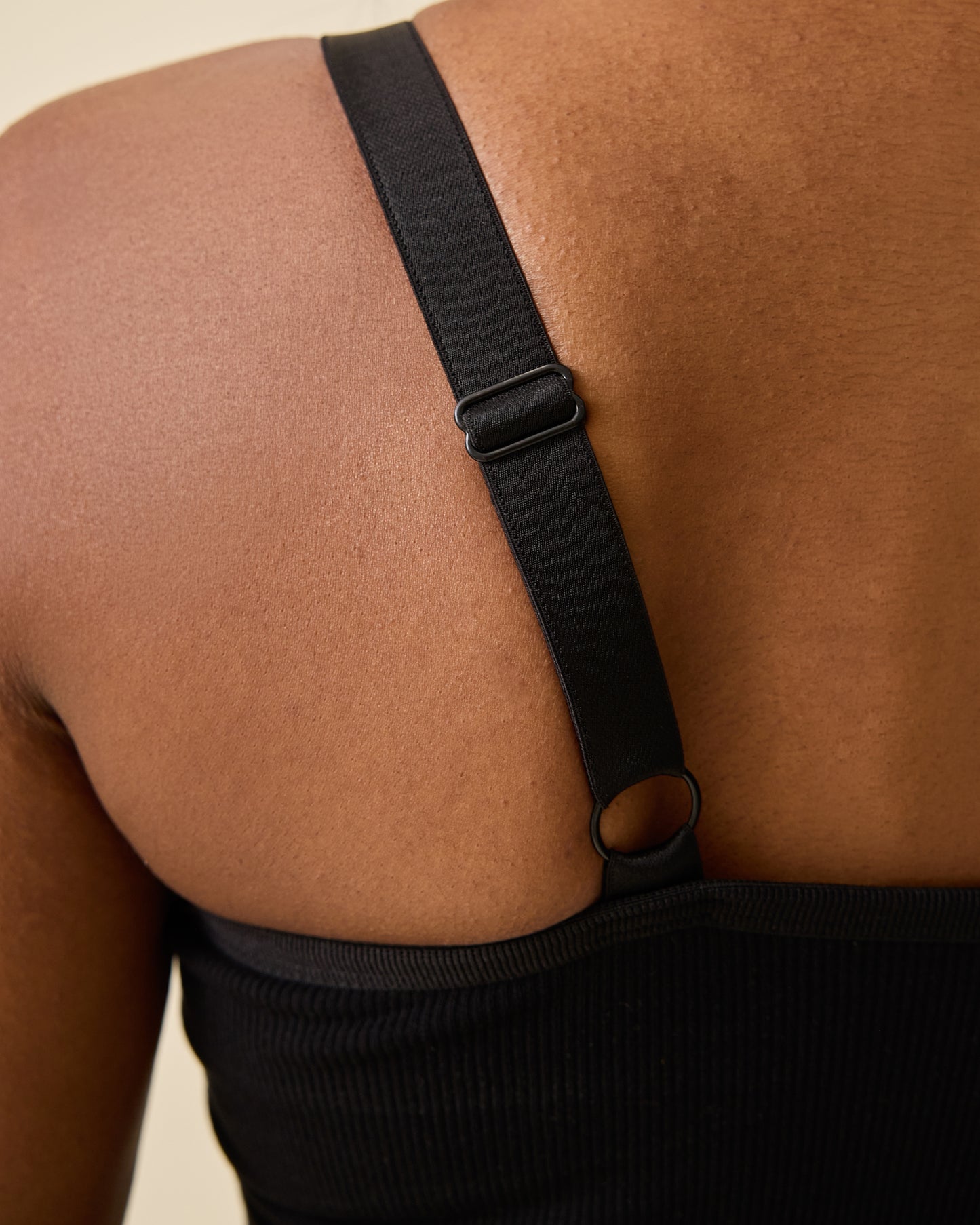 Close up on back view of model wearing Sublime® Bamboo Hands-Free Pumping Lounge & Sleep Bra in Black on a beige background.