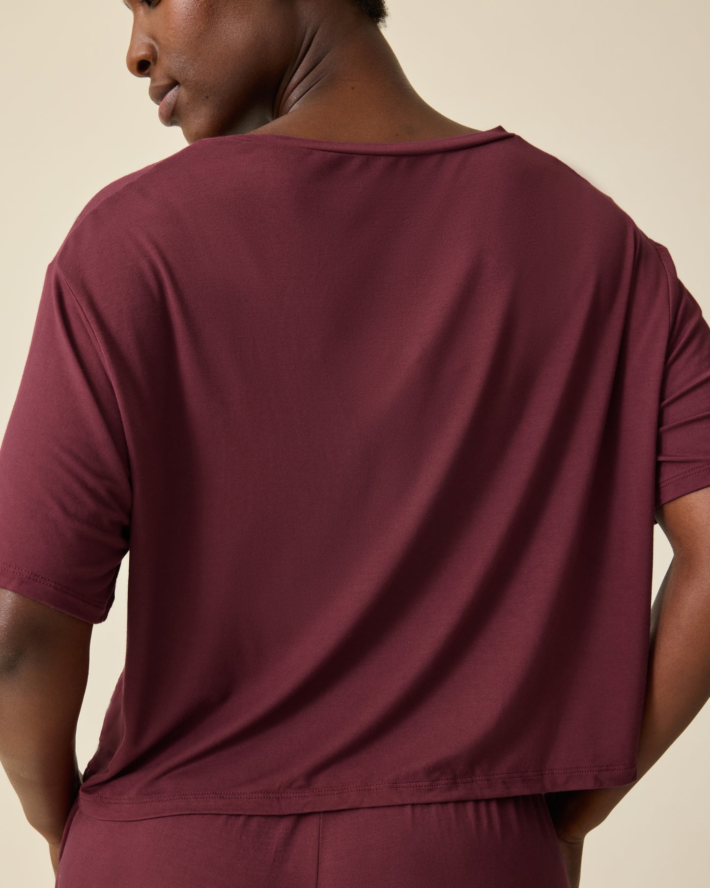 Back view of Aria Bamboo Casual Cropped Short Sleeve Top in Deep Burgundy and Aria Bamboo Casual Lounge Short in Deep Burgundy, on a beige background. 