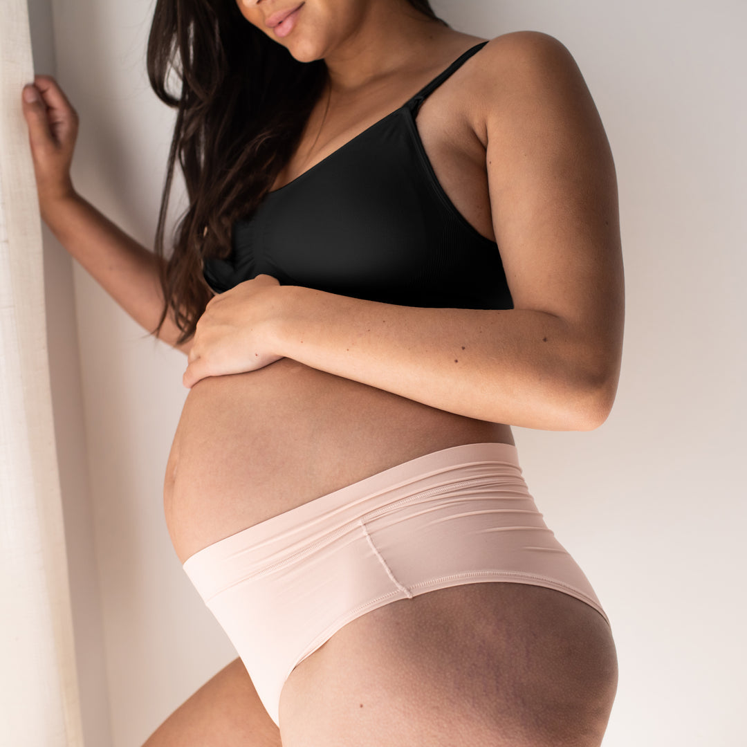 Pregnant model wearing the Grow with Me™ Maternity & Postpartum Hipster in soft pink