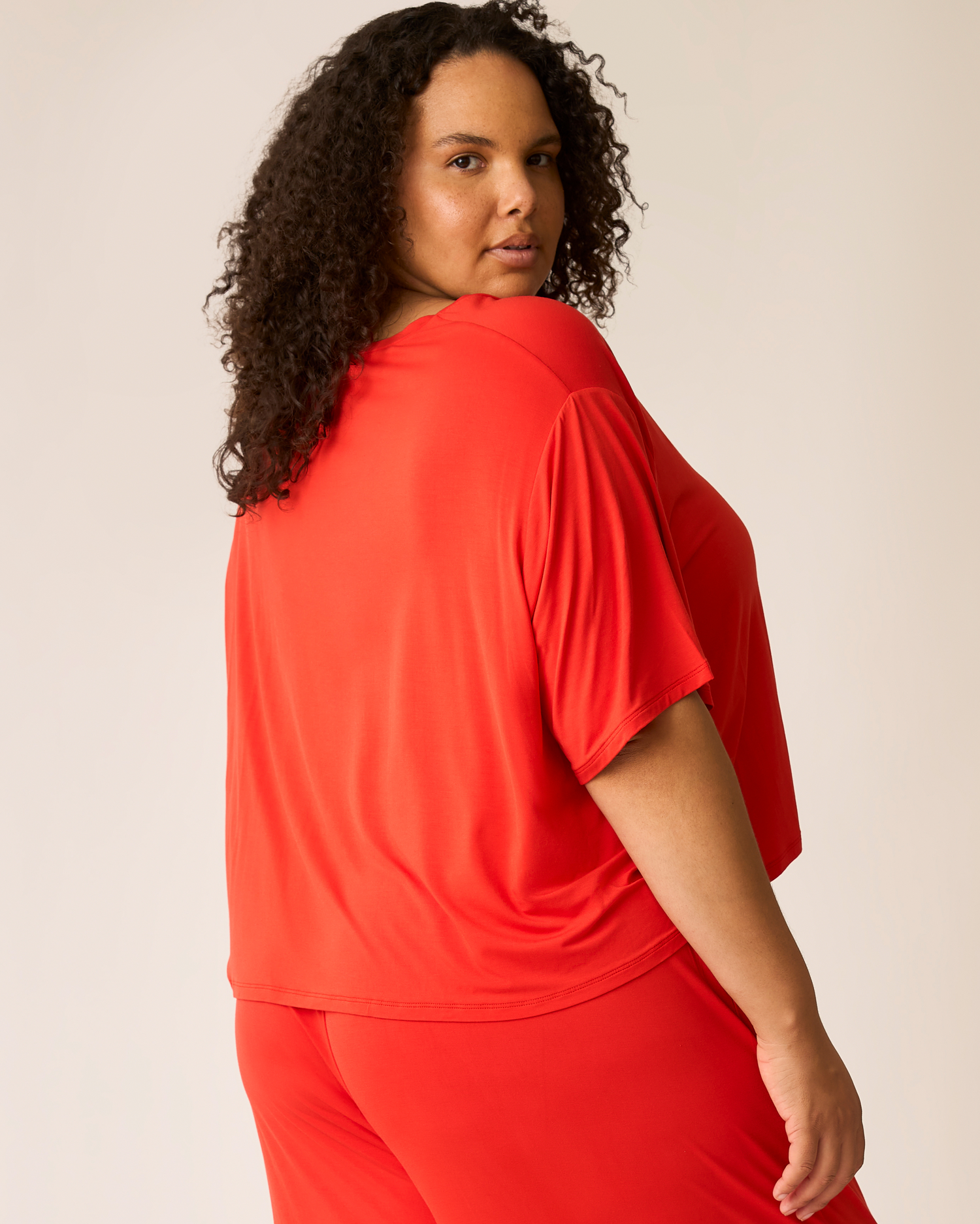 Person wearing a bright red Aria outfit against a plain background
