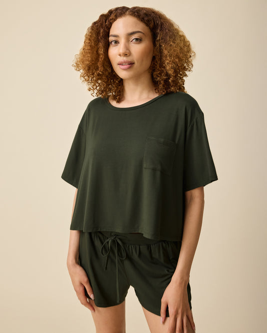 Model is wearing Aria Bamboo Casual Cropped Short Sleeve Top in Thyme and Aria Bamboo Casual Lounge Short in Thyme on a beige background.@model_info:Devyn is wearing a Small.