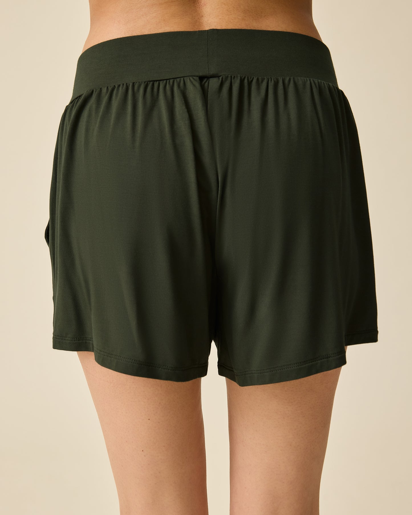 Back view of model wearing Aria Bamboo Casual Lounge Short in Thyme on a beige background.