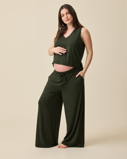 Model is pregnant and wearing Aria Bamboo Cropped V-neck Tank in Thyme and Aria Bamboo Casual Lounge Pant in Thyme on a beige background.@model_info:Tassia is 5'6" and wearing a Medium.