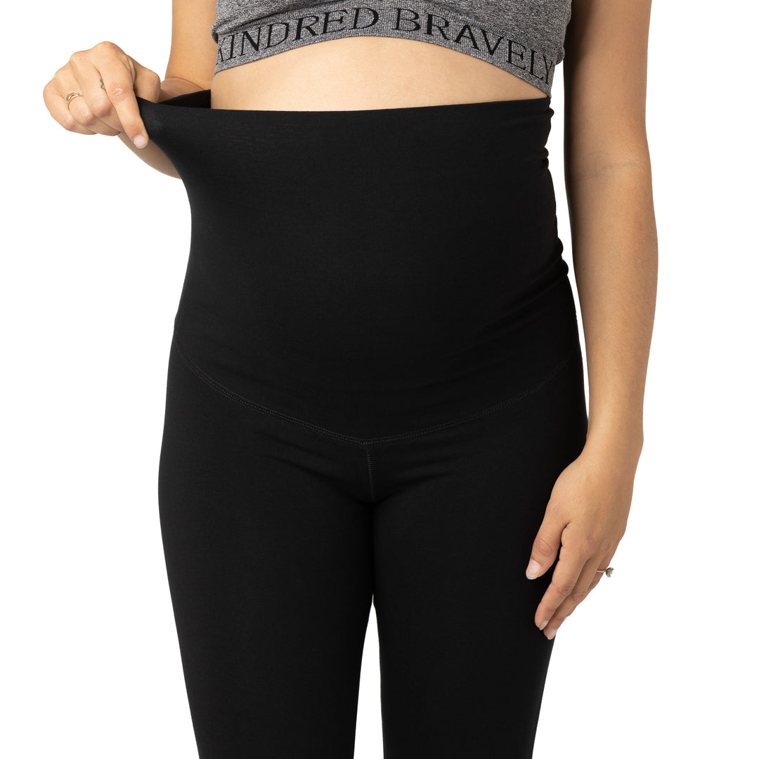 Close-up front view of waist band unfolded on the Cotton Maternity & Postpartum Footless Tight in black on pregnant model