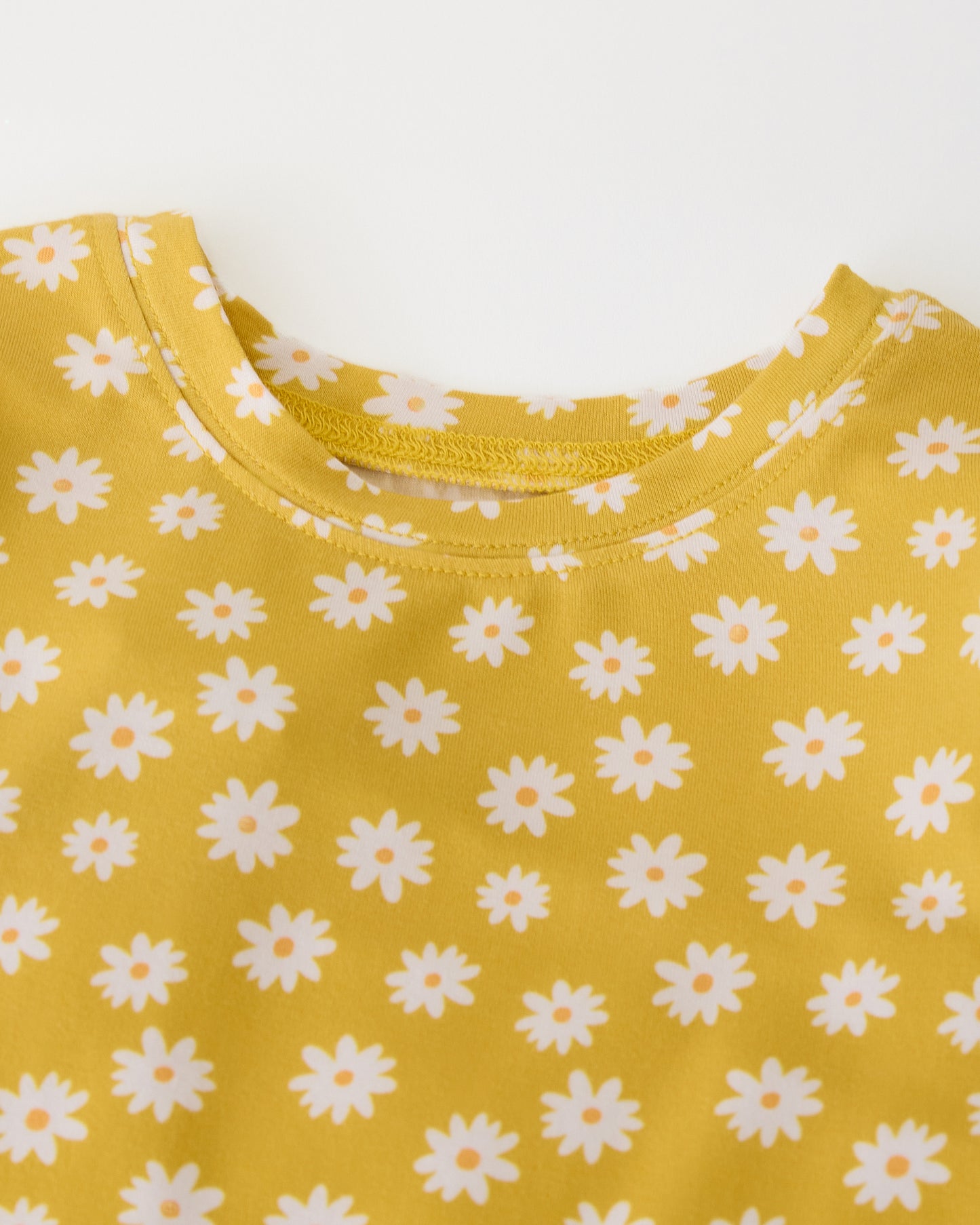 Close up of collar detail on Bamboo Baby Two-Piece Pajama Set in Yellow Daisies on a beige background