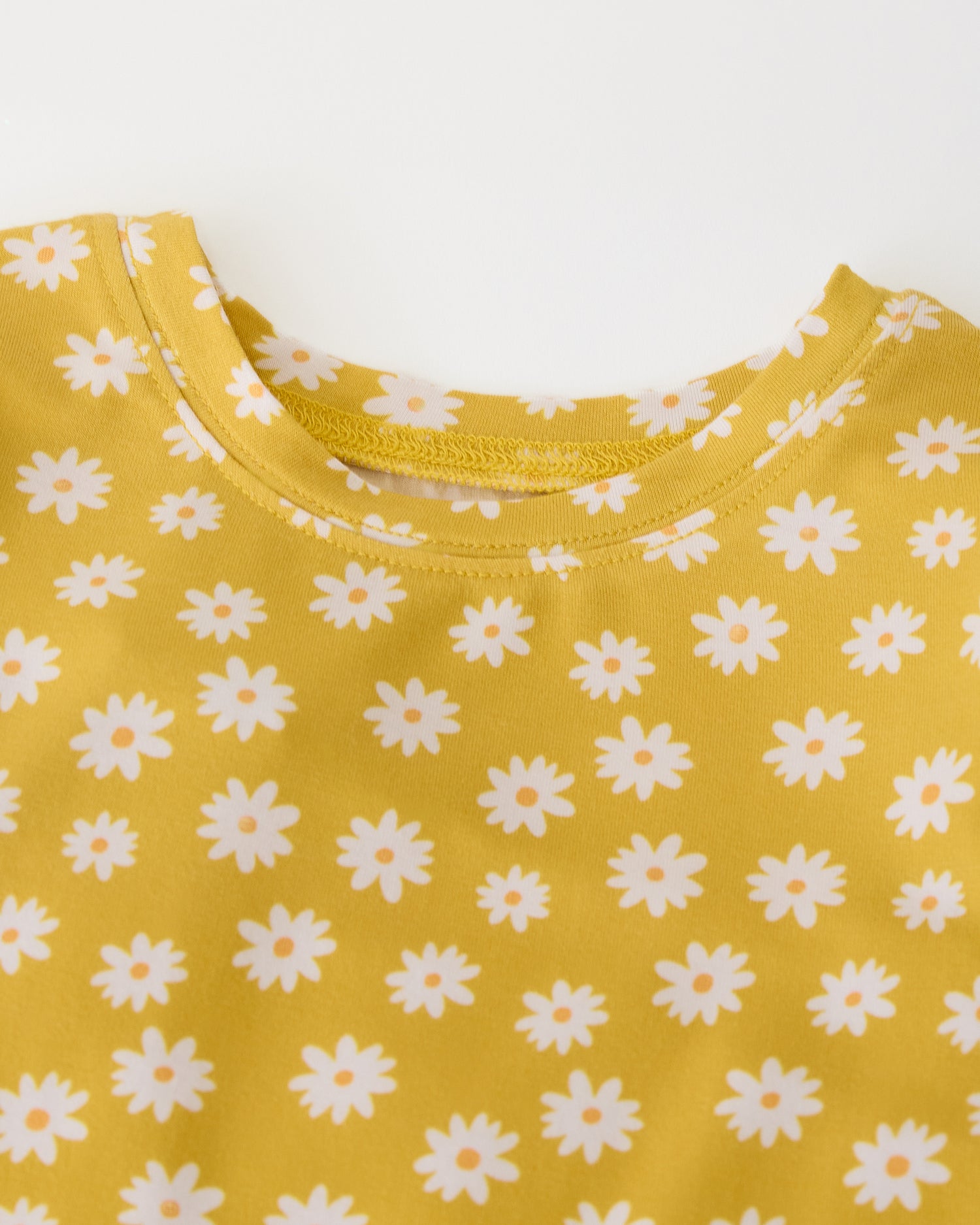Close up of collar detail on Bamboo Baby Two-Piece Pajama Set in Yellow Daisies on a beige background