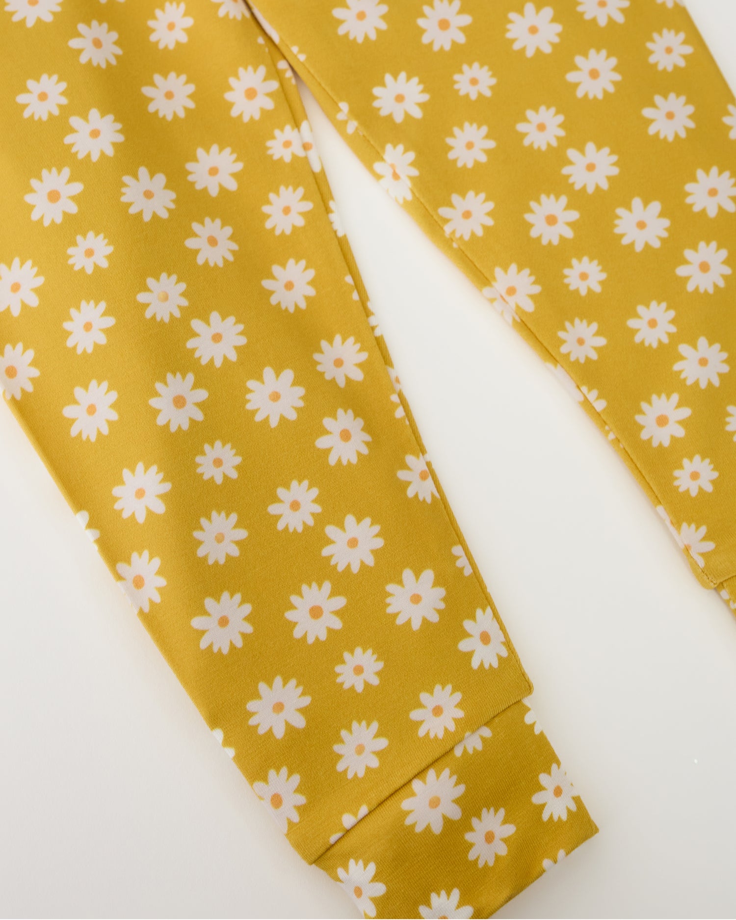 Close up of pants on Bamboo Baby Two-Piece Pajama Set in Yellow Daisies on a beige background