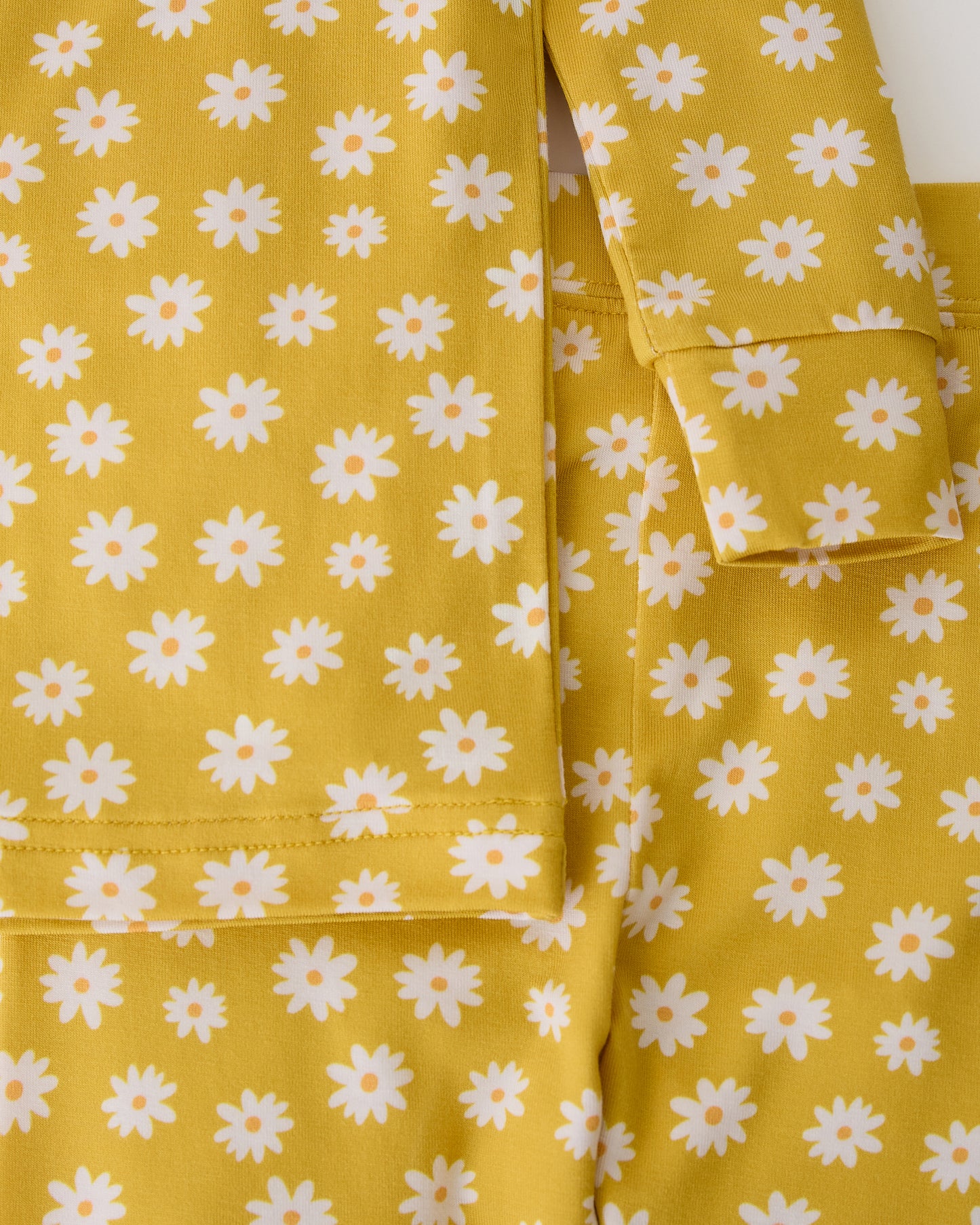 Close up on sleeves on Bamboo Baby Two-Piece Pajama Set in Yellow Daisies on a beige background