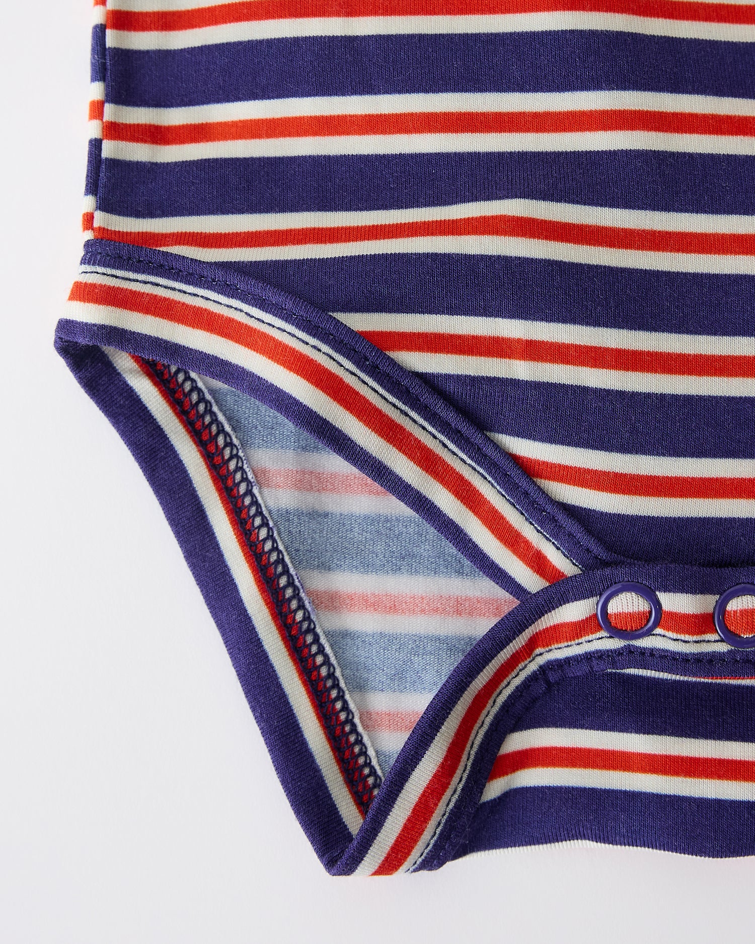 Close up of snap closure on Baby Onesie Two-Pack in Red & Blue Stripe on a beige background