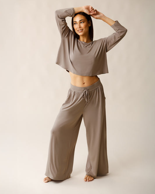 Woman wearing the Aria Bamboo Casual Lounge Pant in Taupe, paired with matching Aria Bamboo Casual Cropped Long Sleeve Top, with arms overhead@model_info:Lisa is 5'6" and wearing a Small.