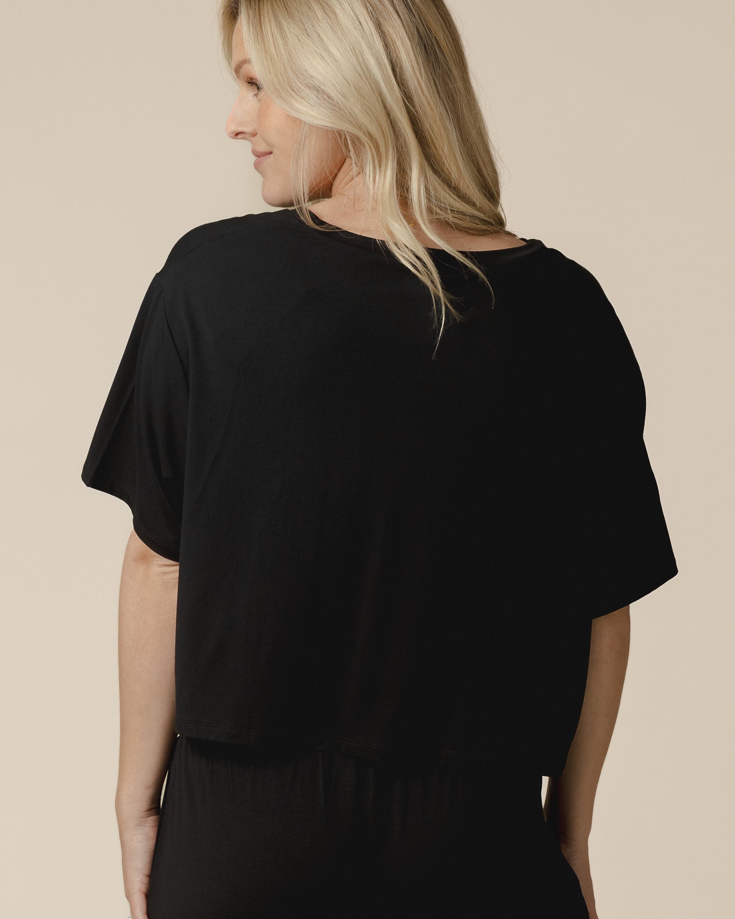 Back view of model wearing the Aria Bamboo Casual Cropped Short Sleeve Top in Black