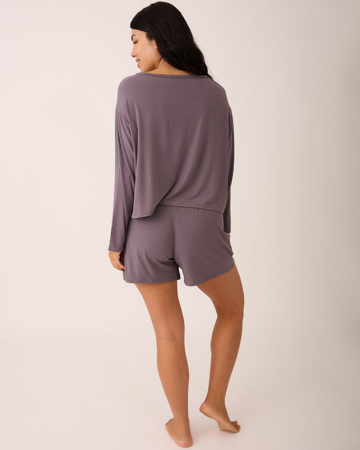Back view of model wearing Aria Bamboo Casual Lounge Short in Granite with side pockets and a drawstring waist, paired with Aria Bamboo Casual Cropped Long Sleeve Top in Granite against a beige background.