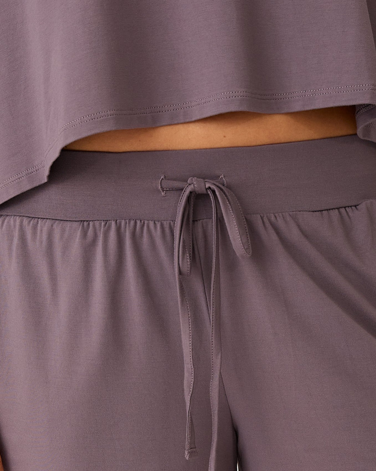 Close up of Aria Bamboo Casual Cropped Short Sleeve Top in Granite and detail of drawstring on the Aria Bamboo Casual Lounge Pant in Granite on a beige background.