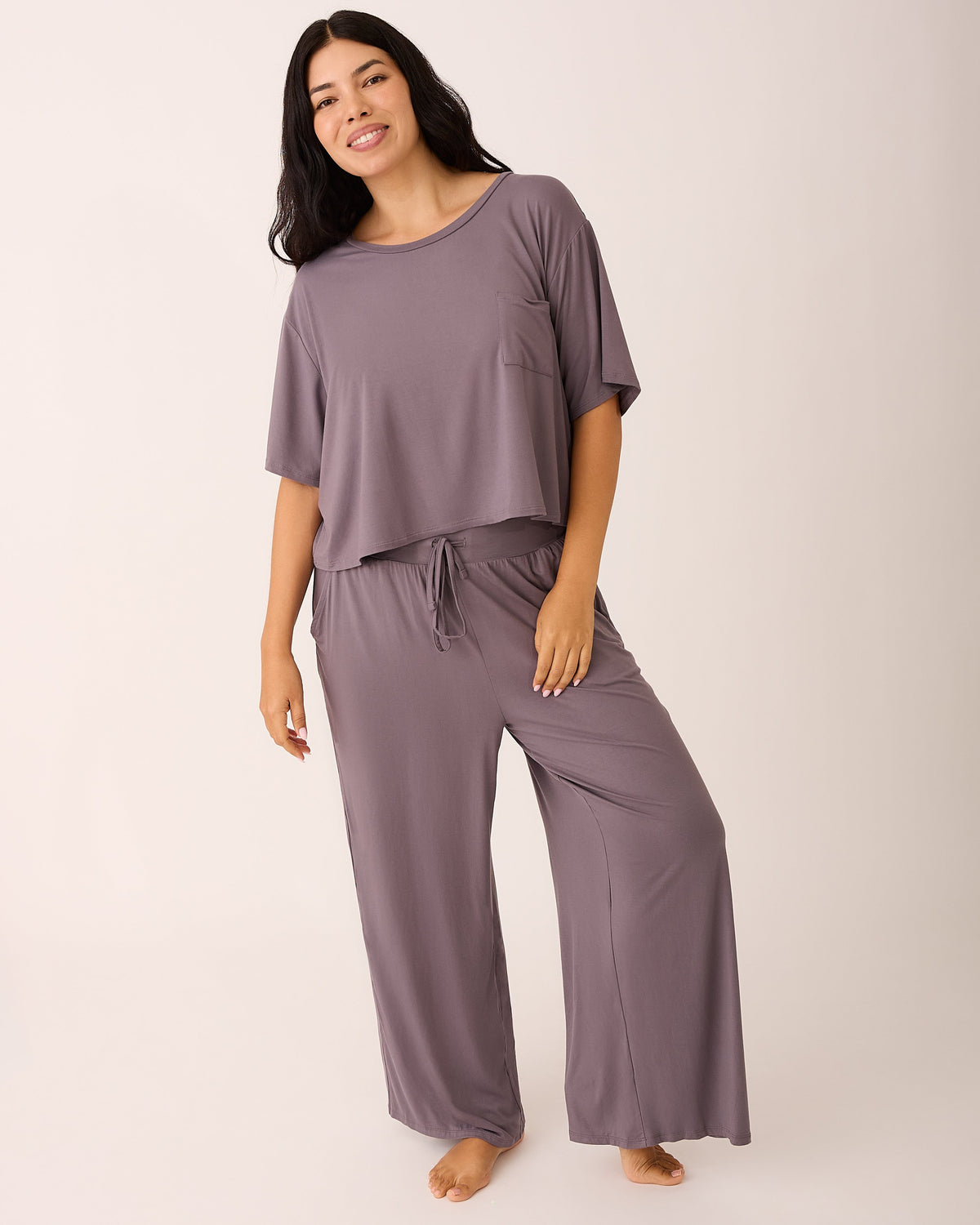 Model is wearing Aria Bamboo Casual Cropped Short Sleeve Top in Granite and Aria Bamboo Casual Lounge Pant in Granite on a beige background.