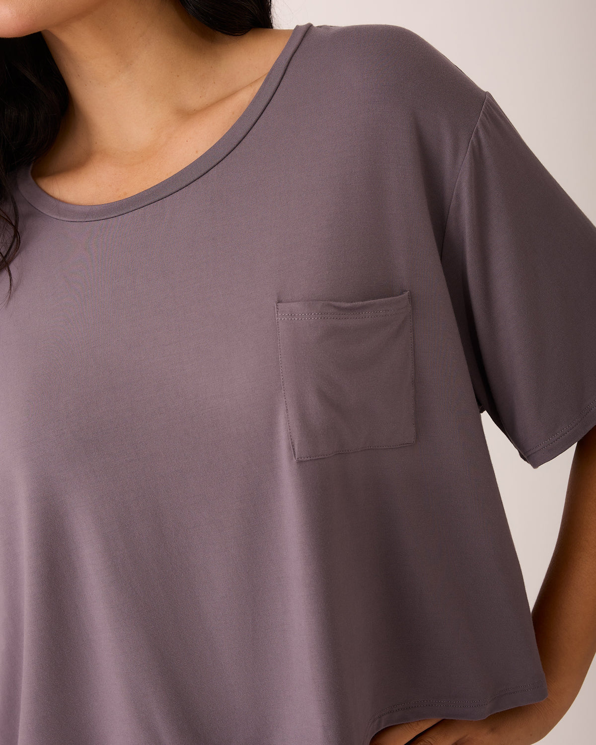 A close up of model wearing Aria Bamboo Casual Cropped Short Sleeve Top in Granite on a beige background.