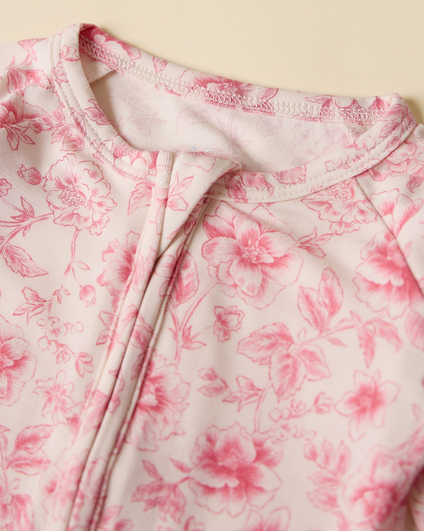 Close-up of pink floral pattern on Bamboo Baby Pajama in pink toile on a beige background