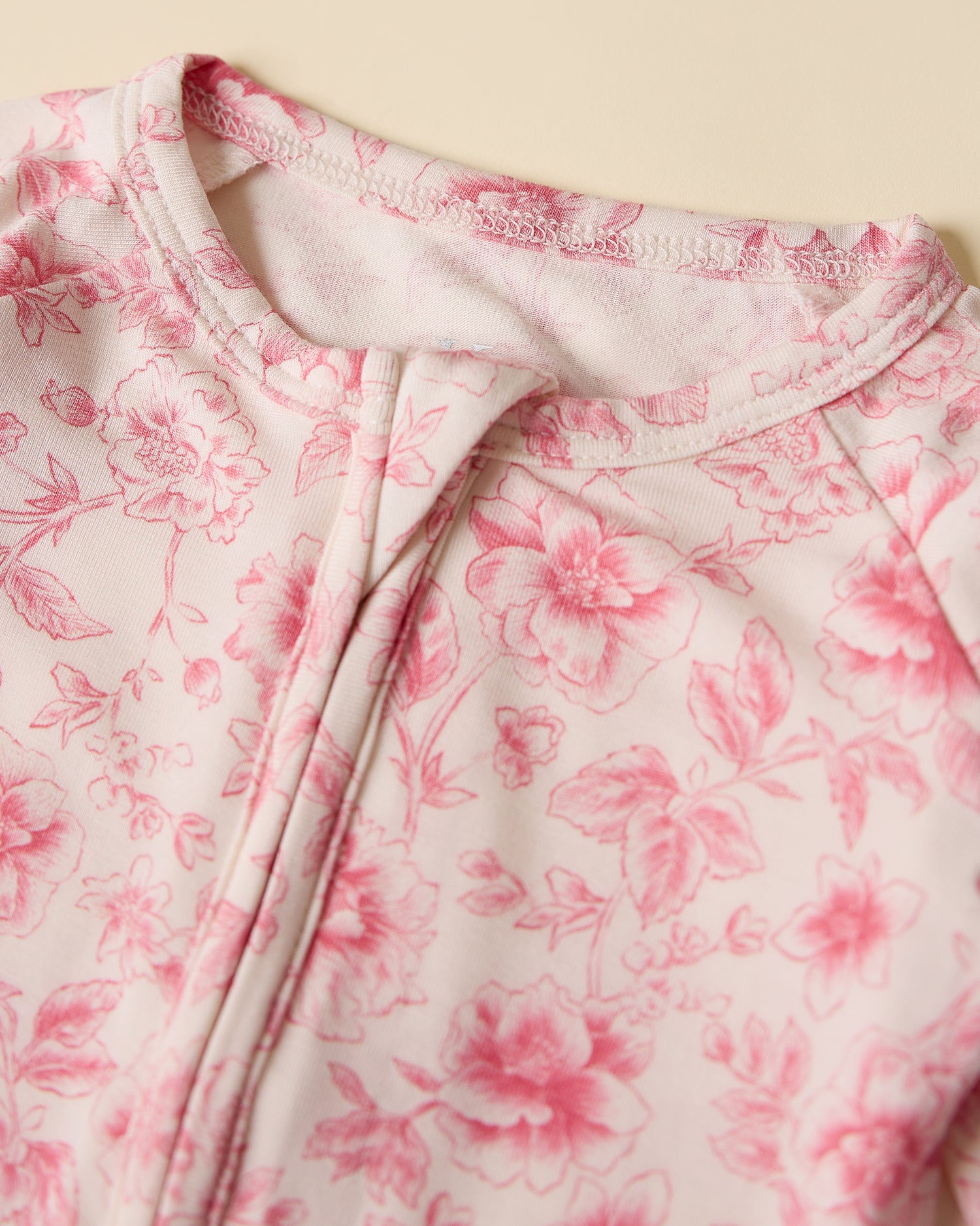 Close-up of pink floral pattern on Bamboo Baby Pajama in pink toile on a beige background