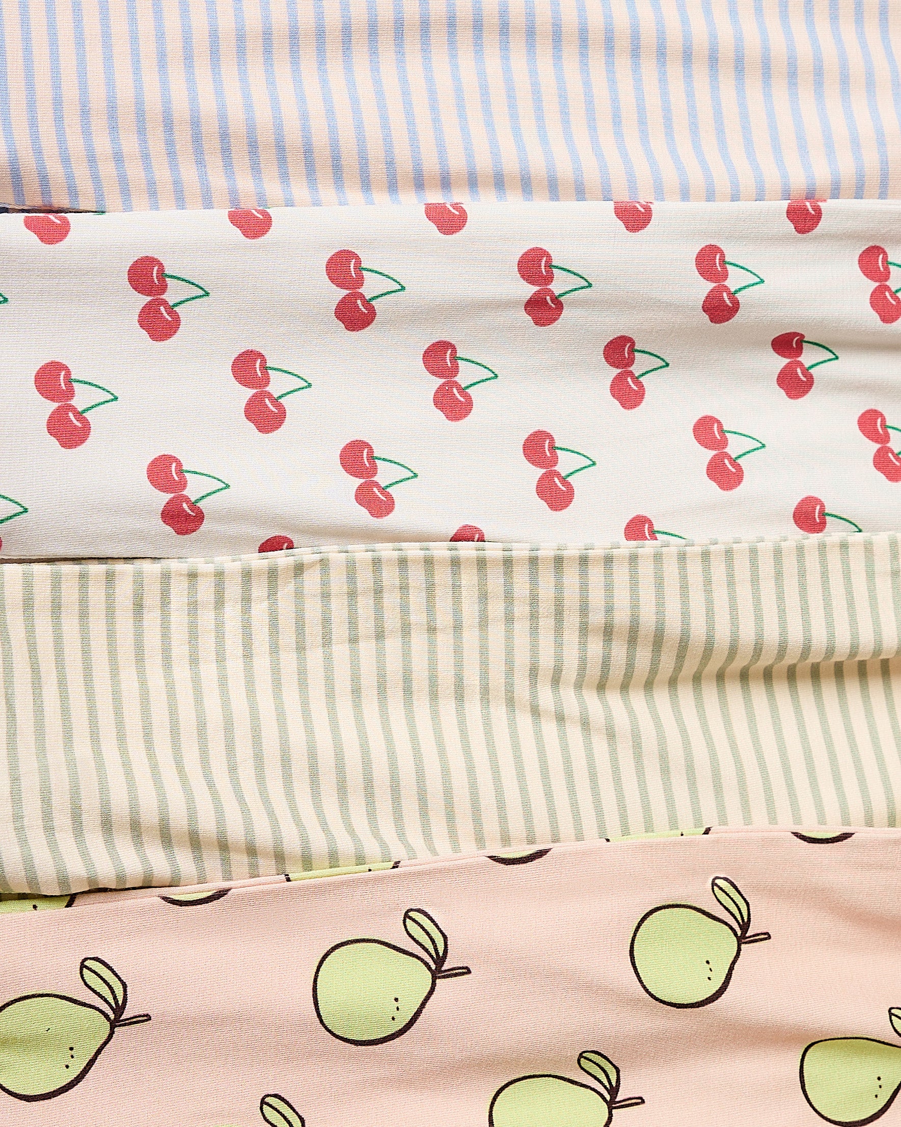 Collection of fabric swatches from Bamboo Baby Pajamas with cherry, pomelo, and striped patterns.