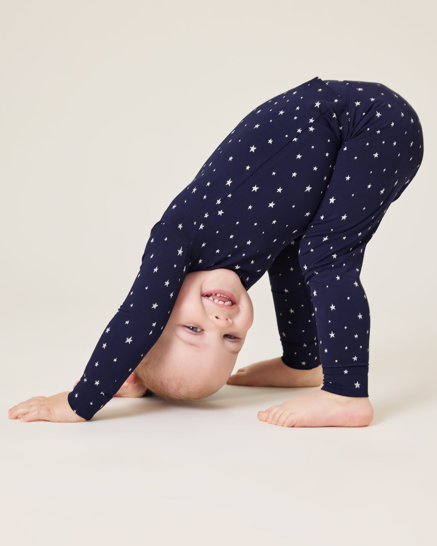 Baby bending down playing wearing the Bamboo Baby Two-Piece Pajama Set in Navy Stars print