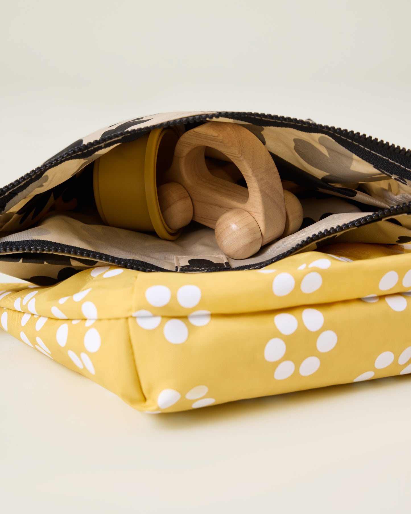 Opened Quick Change Kit Bag in Sunshine Dots print, on a neutral background, showing wooden toys inside