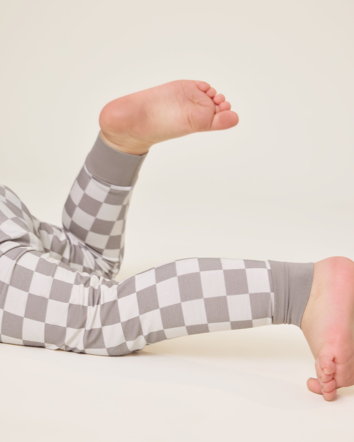 Close up of Baby lying down wearing the Bamboo Baby Two-Piece Pajama Set in Taupe Checker print