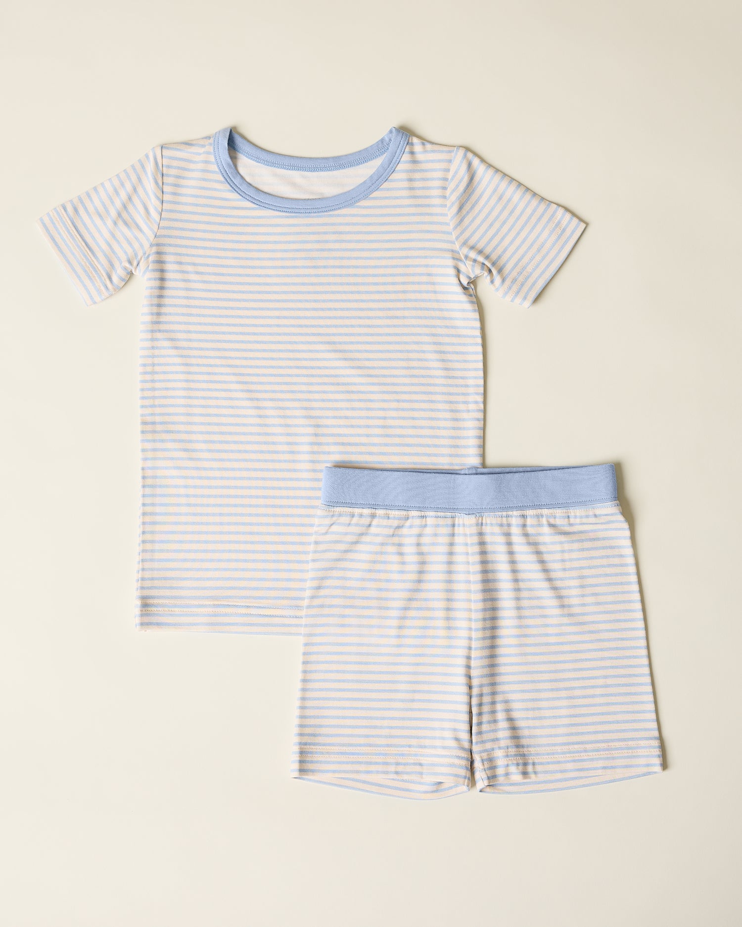 Children's striped short sleeve and shorts pajama set with blue stripes and accents on a beige background