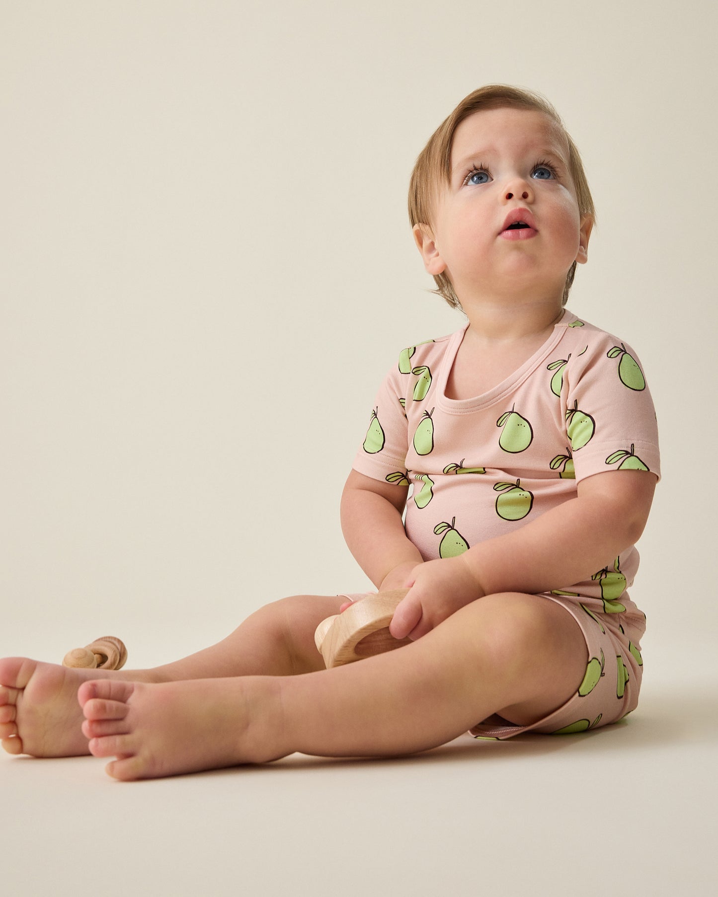 Baby wearing the Bamboo Short Sleeve & Shorts Set in pink pomelo on a beige background