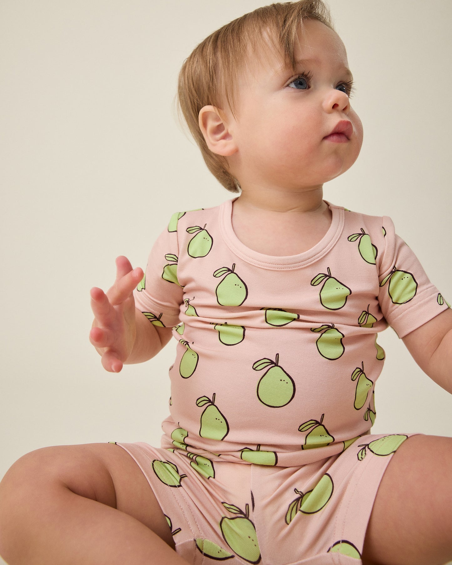 Baby wearing the Bamboo Short Sleeve & Shorts Set in pink pomelo on a beige background