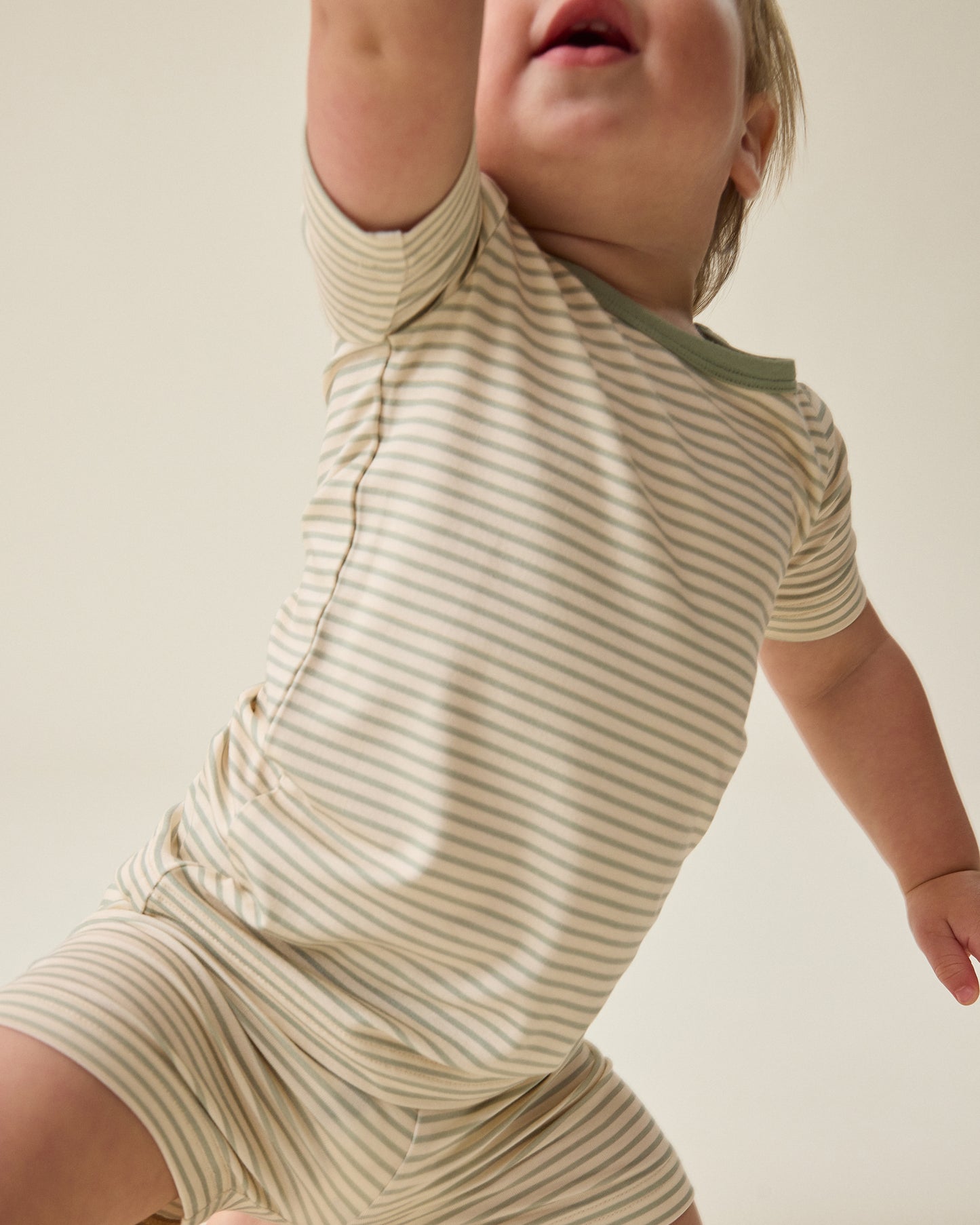 Baby wearing the Bamboo Short Sleeve & Shorts Set in sage green stripe against a plain background