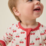 Baby wearing the Bamboo Baby Pajama with cherry pattern on a beige background