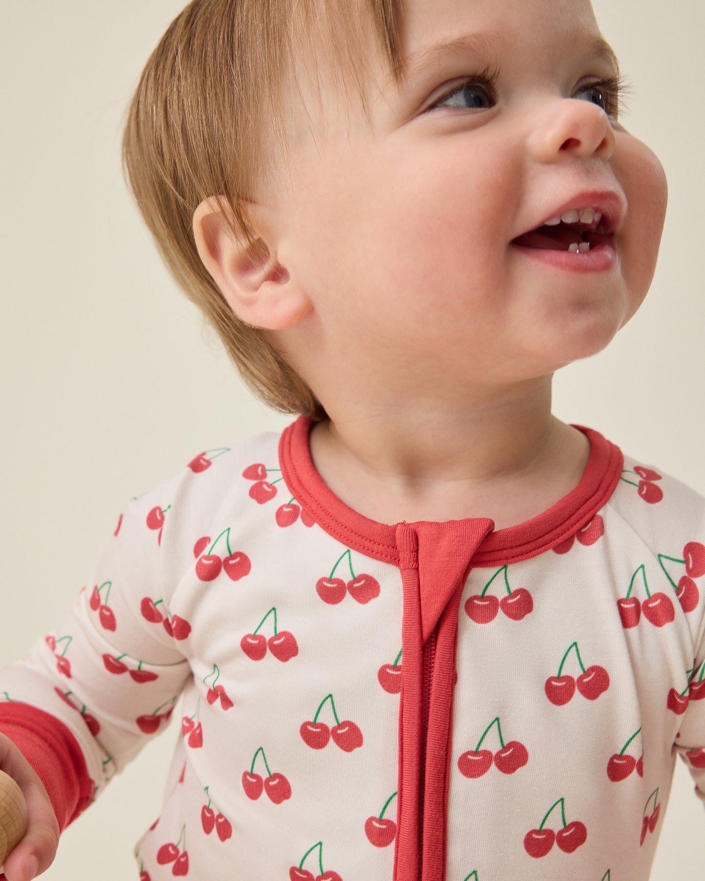 Baby wearing the Bamboo Baby Pajama with cherry pattern on a beige background
