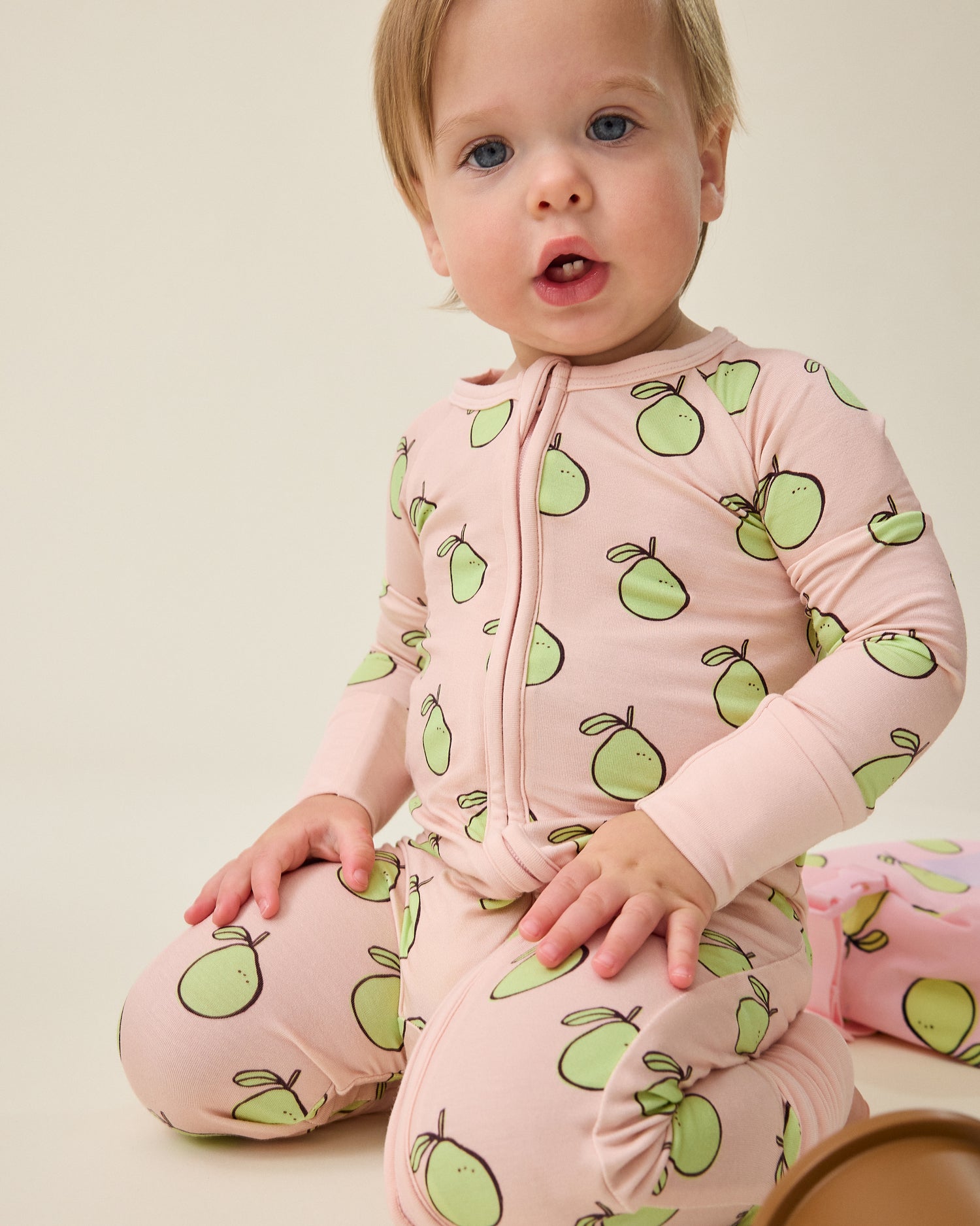 Baby wearing a pink outfit with green pomelo patterns@model_info:Noa is wearing 6-12 months.