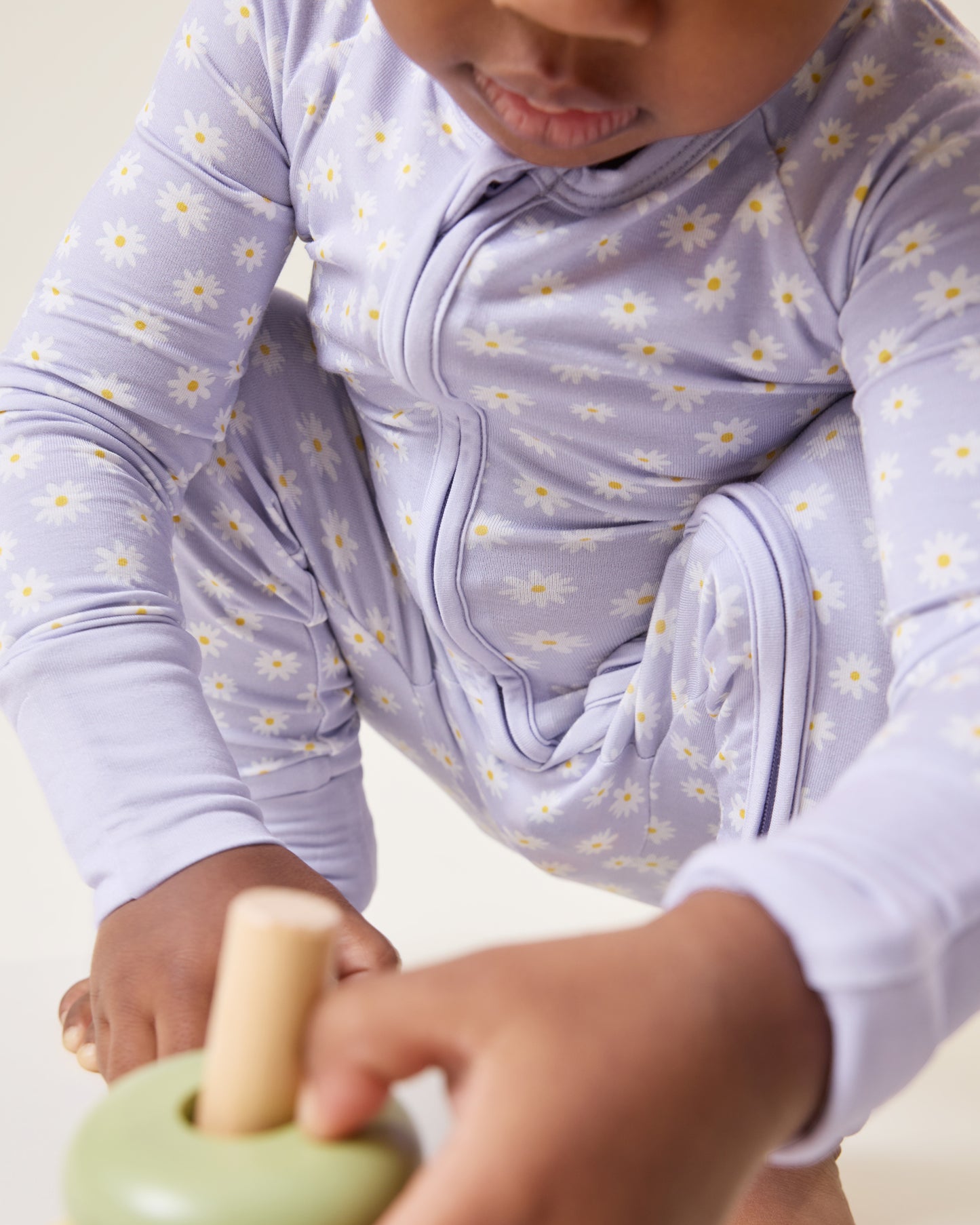 Baby bending down and playing, wearing the Bamboo Baby Pajama in Purple Daisies print