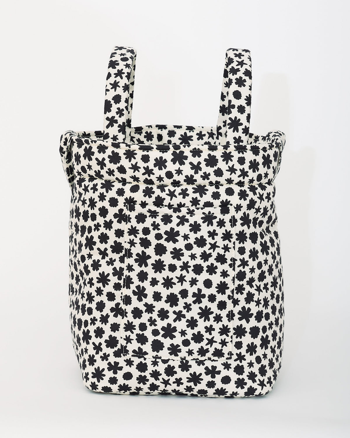 Stroller Party™ Bucket Bag in Cream Chamomiles is sitting upright, on a beige background.