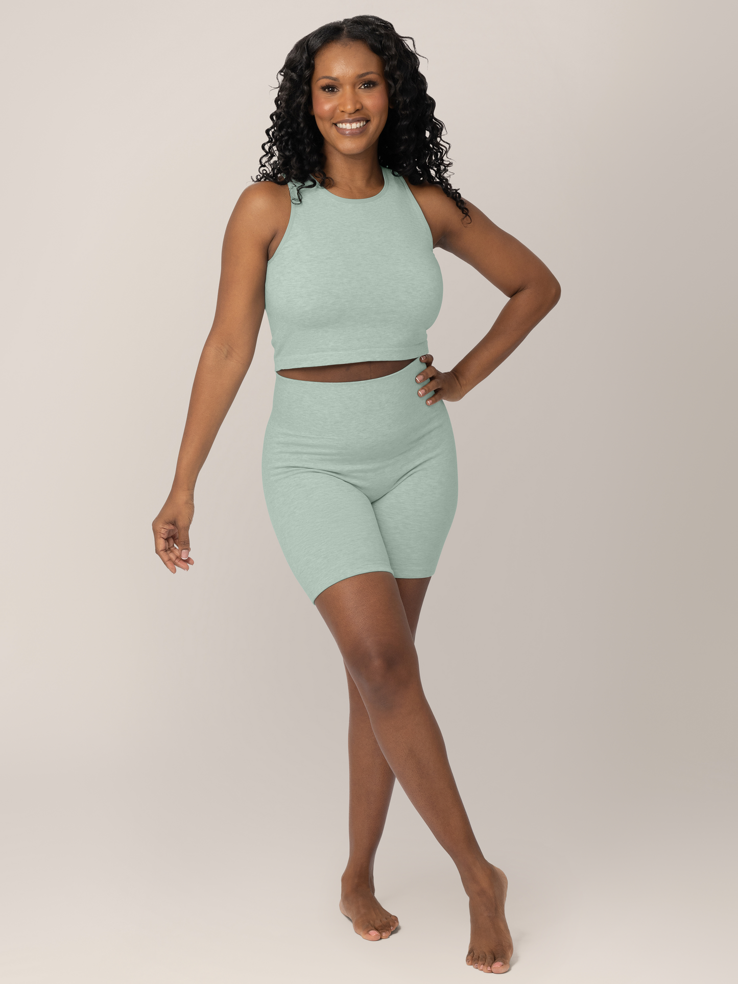 Full body front view of model holding baby and wearing the Sublime® Bamboo Maternity & Postpartum Bike Short in Dusty Blue Green Heather, paired with the matching Sublime® Bamboo Maternity & Nursing Longline Bra.